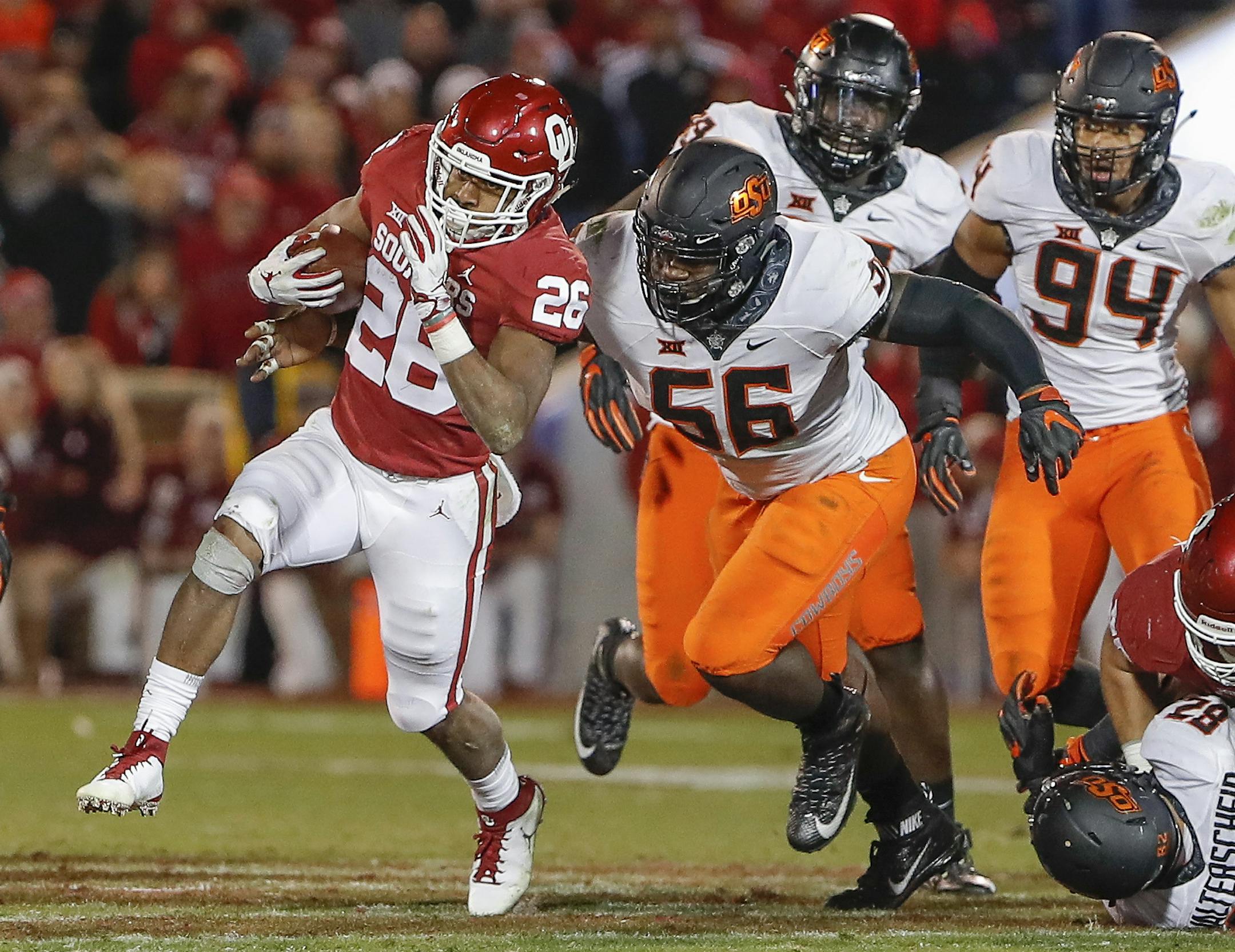 Oklahoma running back Kennedy Brooks (26) runs the ball ahead of Oklahoma State defensive tackle Enoch Smith Jr. (56) in the second half of an NCAA college football game in Norman, Okla., Saturday, Nov. 10, 2018. Oklahoma won 48-47. (AP Photo/Alonzo Adams)