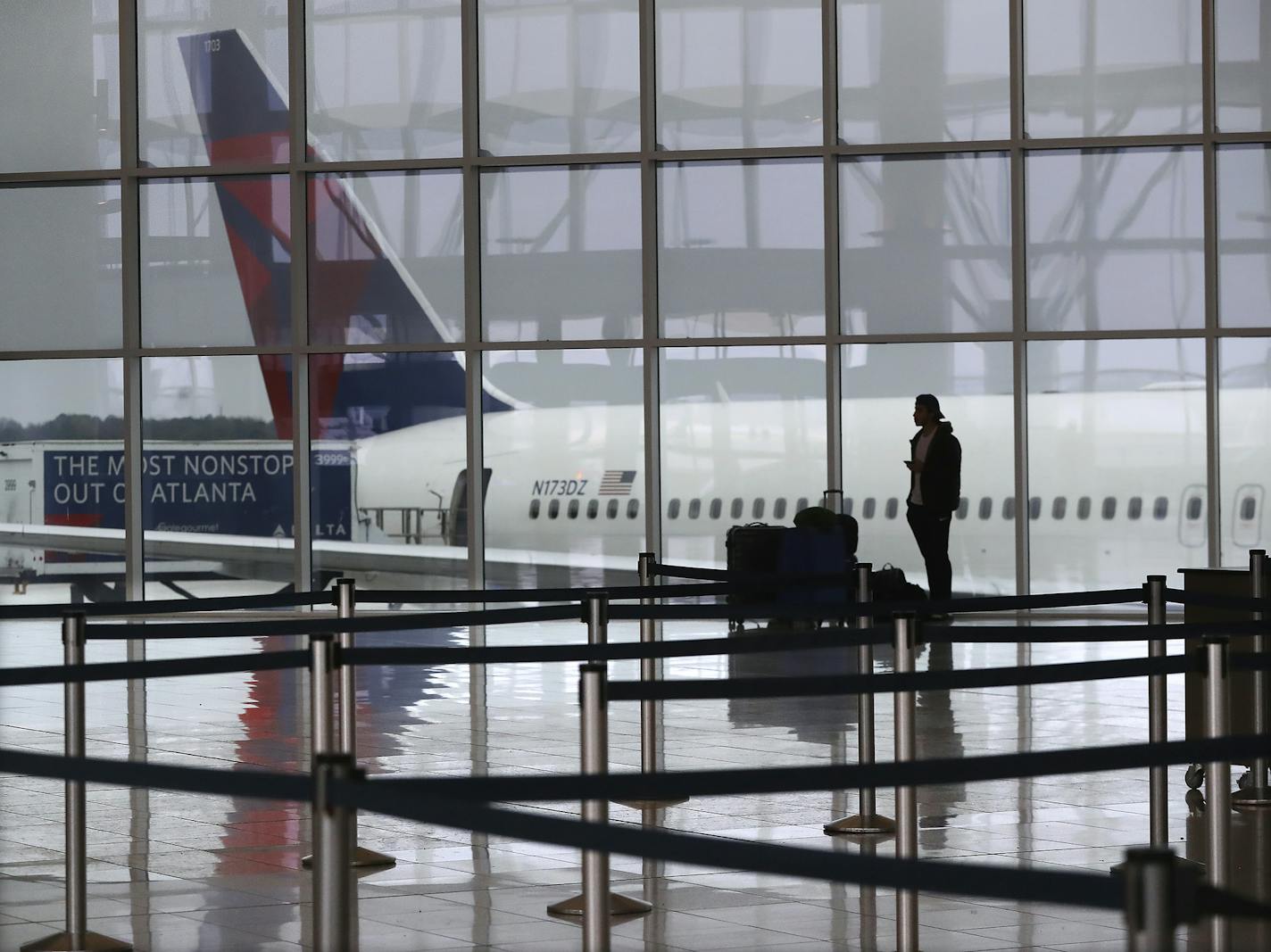 Delta said Wednesday it will cut its flight capacity by 70%. It also said 10,000 workers have taken unpaid voluntary leave and asked more to do so. File photo of a passenger at a Delta gate at Atlanta-Hartsfield International Airport.