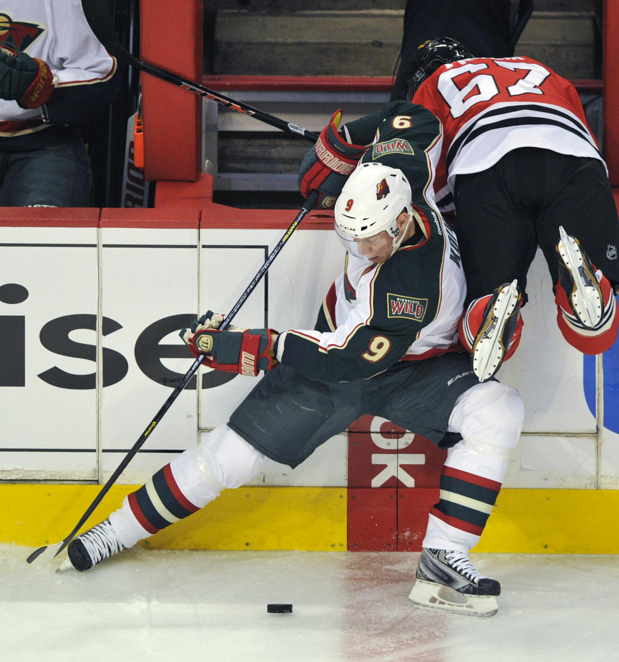 Minnesota Wild's Mikko Koivu (9) tries to control the puck as Chicago Blackhawks' Michael Frolik (67) crashes over the boards during the first period of Game 1 of an NHL hockey Stanley Cup playoff series, Tuesday, April 30, 2013, in Chicago. (AP Photo/Jim Prisching)