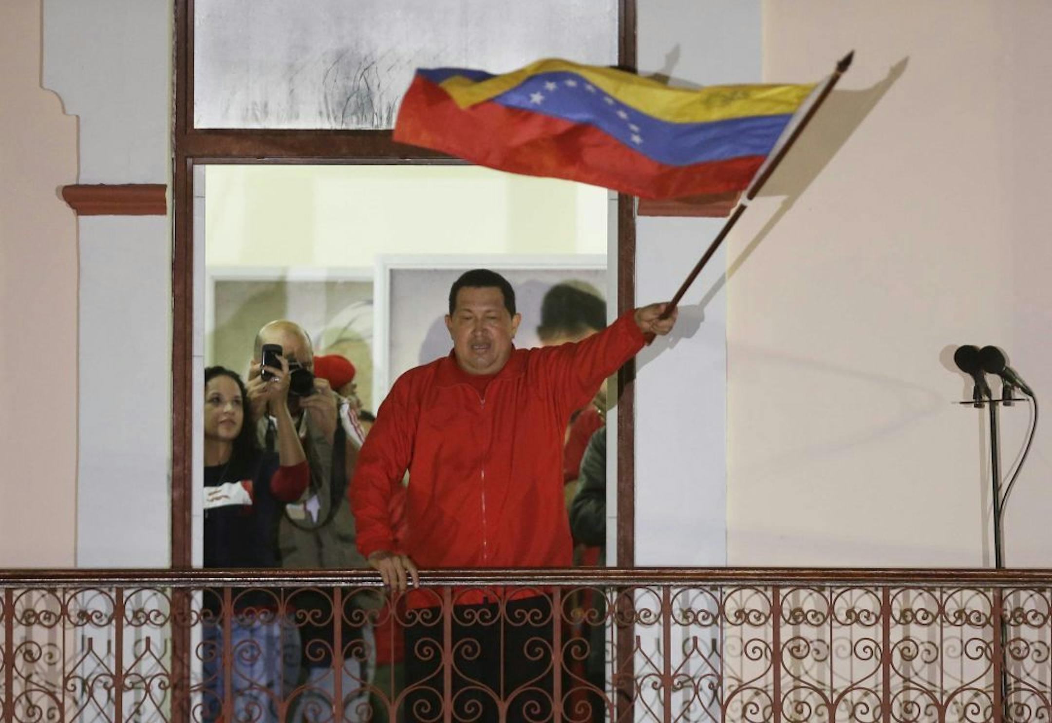 Venezuela's President Hugo Chavez waves a Venezuelan flag as he greets supporters at the Miraflores presidential palace balcony in Caracas, Venezuela, Sunday, Oct. 7, 2012. Chavez won re-election and a new endorsement of his socialist project Sunday, surviving his closest race yet after a bitter campaign against opposition candidate Henrique Capriles.