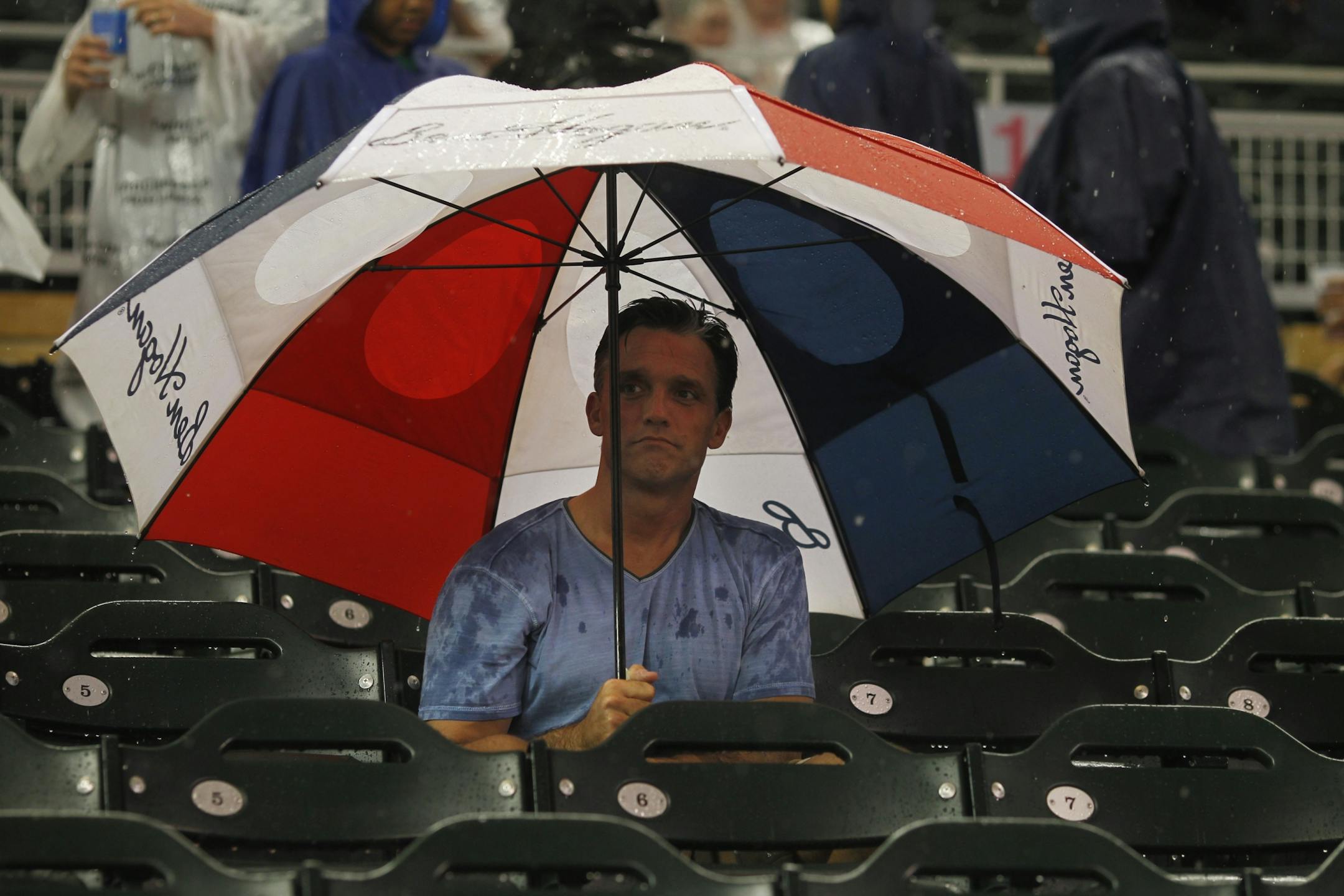 At Target Field in a game between the Twins and the Tigers, this Twins fan used an umbrella to keep the hail and rain from his head.