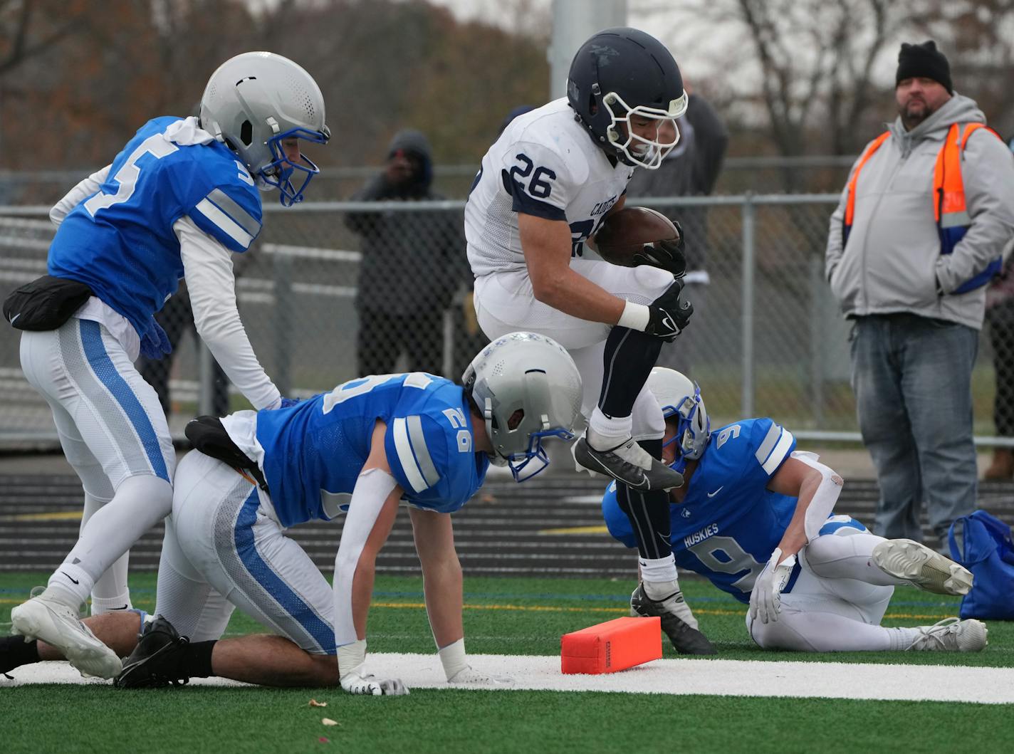 St. Thomas Academy running back Savion Hart (26) holds on to his knee as he jumps over Owatonna defense in the second half during a Class 5A state quarterfinal in Woodbury, Minn., on Saturday, Nov. 11, 2023.