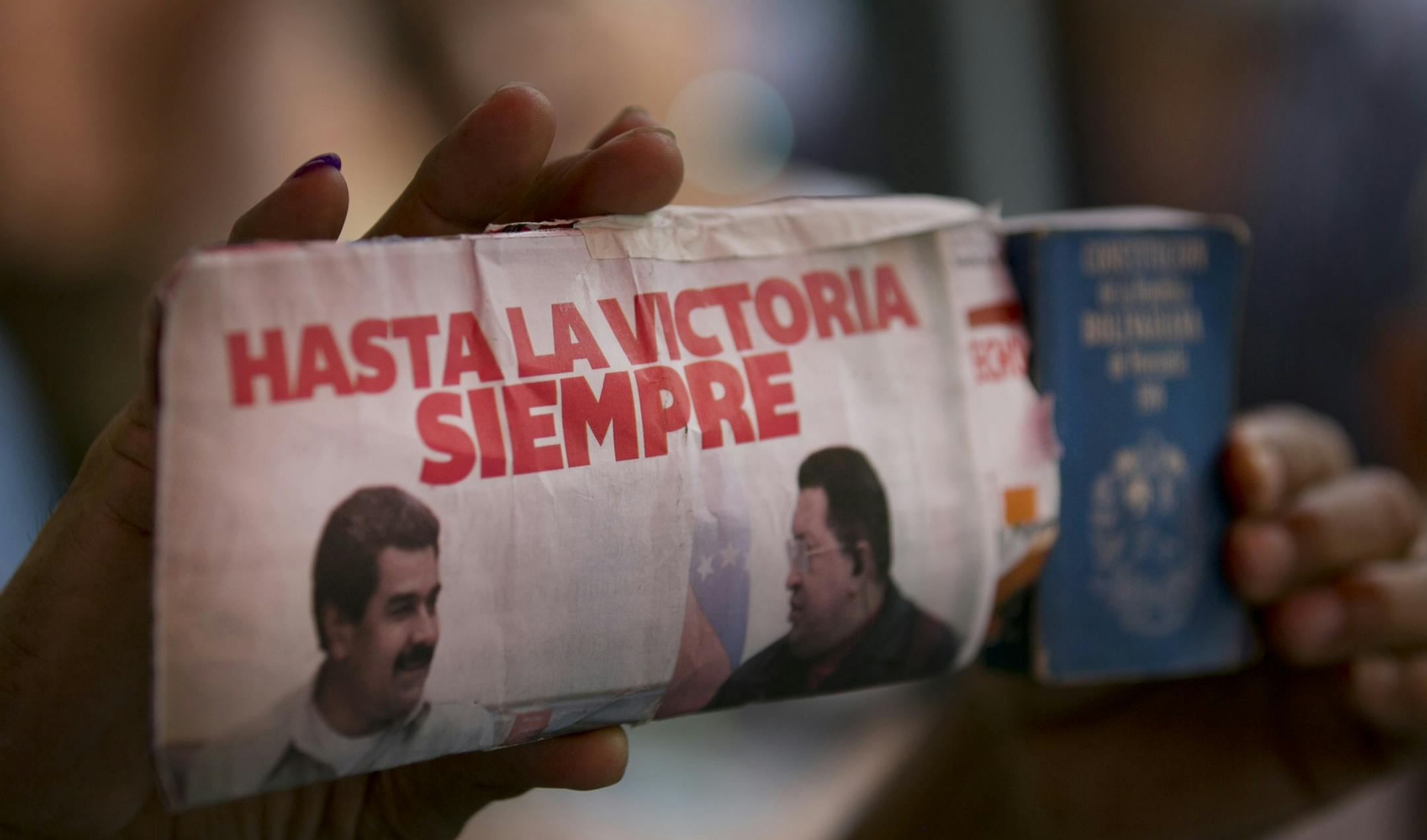 A pro-government supporter holds a leaflet showing Venezuela's President Nicolas Maduro, left, and Venezuela's late president Hugo Chavez and reading in Spanish "Always towards victory," outside of the National Assembly building during a session in Caracas, Venezuela, Thursday, Dec.10, 2015. VMembers of the National Assembly vote an article of the national budget during a session in Caracas, Venezuela, Thursday, Dec. 10, 2015. Venezuela's ruling socialist party is set to rush through a series of