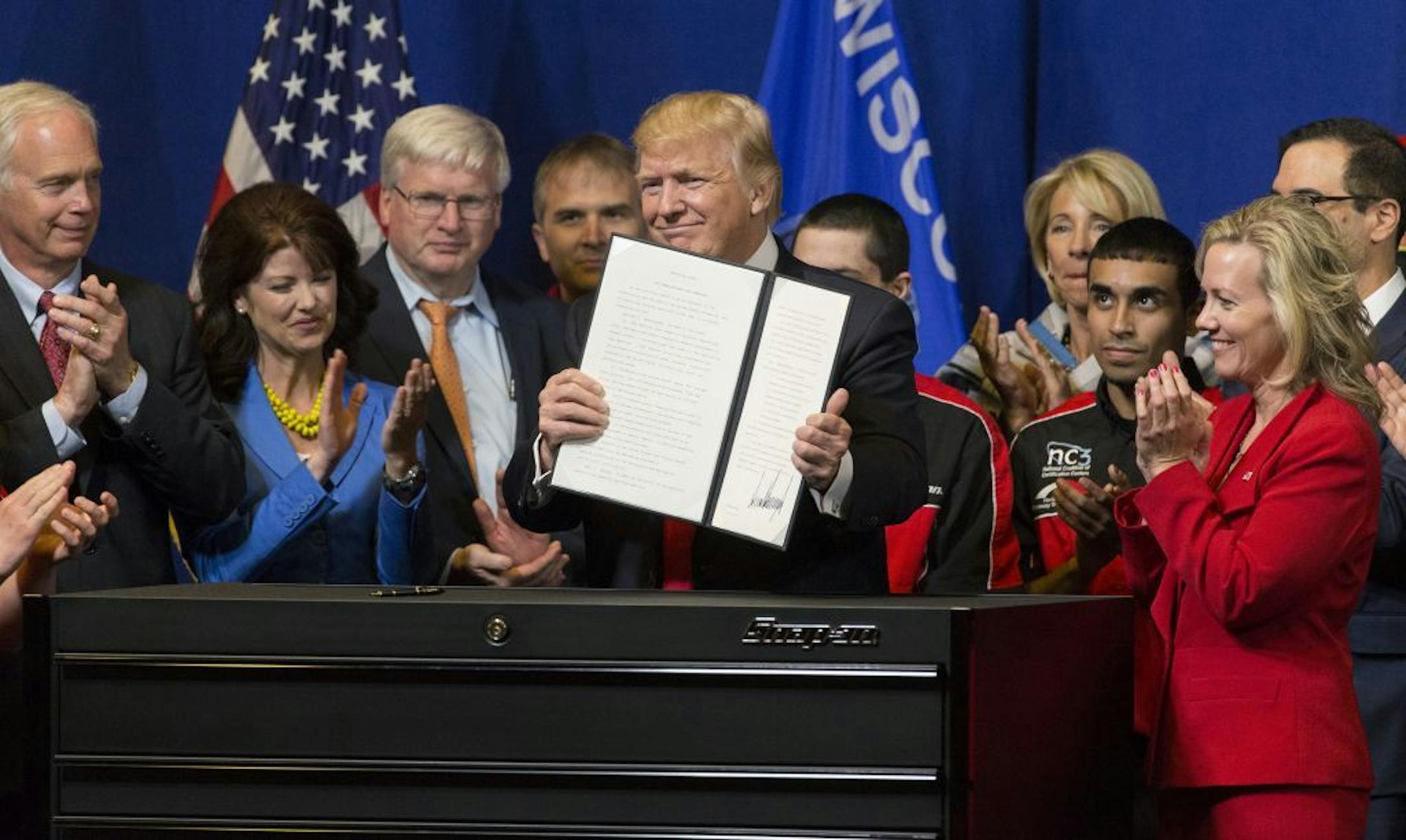 President Donald Trump signs the so-called "Buy American, Hire American" executive order on Tuesday, April 18, 2017 during a visit to Snap-on Inc. in Kenosha, Wis. The orders clamp down on guest worker visas and require federal agencies to buy more goods and services from U.S. companies and workers.