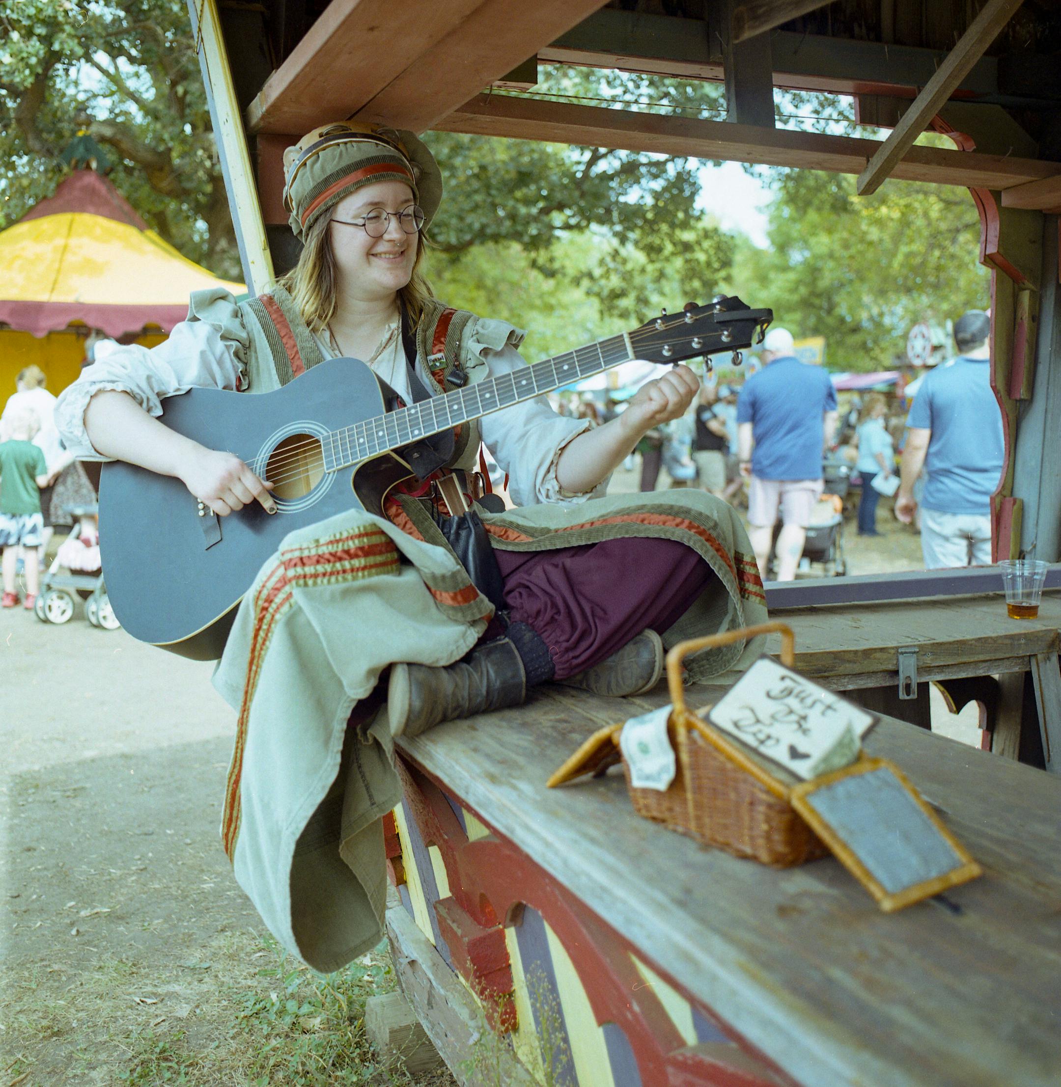 Rian Vellichor tunes her guitar. "There is nothing like performing at a Renaissance Festival [...] it combines a nerdy sensibility with playing music," she said.