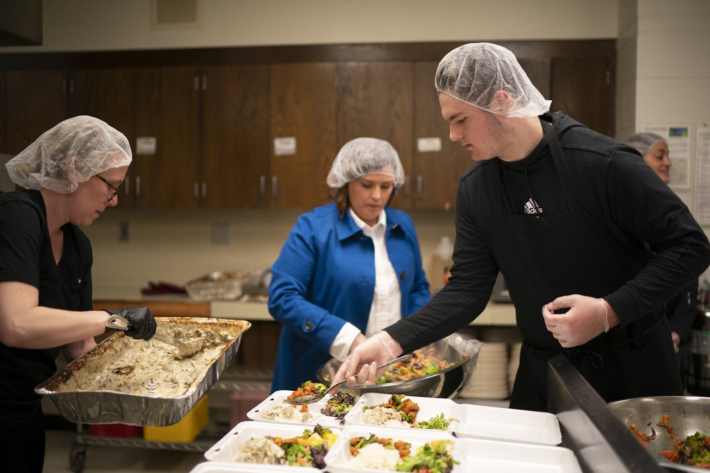 Liz Mullen, Chowgirls Killer Catering executive chef, left, Allison O'Toole, Second Harvest Heartland CEO, and volunteer Ty Larsen assembled meals in the kitchen of Hope Presbyterian Church Monday evening. ] JEFF WHEELER • Jeff.Wheeler@startribune.com Minnesota Central Kitchen, a coordinated effort of Second Harvest Heartland with Loaves and Fishes and Chowgirls Killer Catering produced meals at Hope Presbyterian Church Monday, evening March 30, 2020 in Richfield.