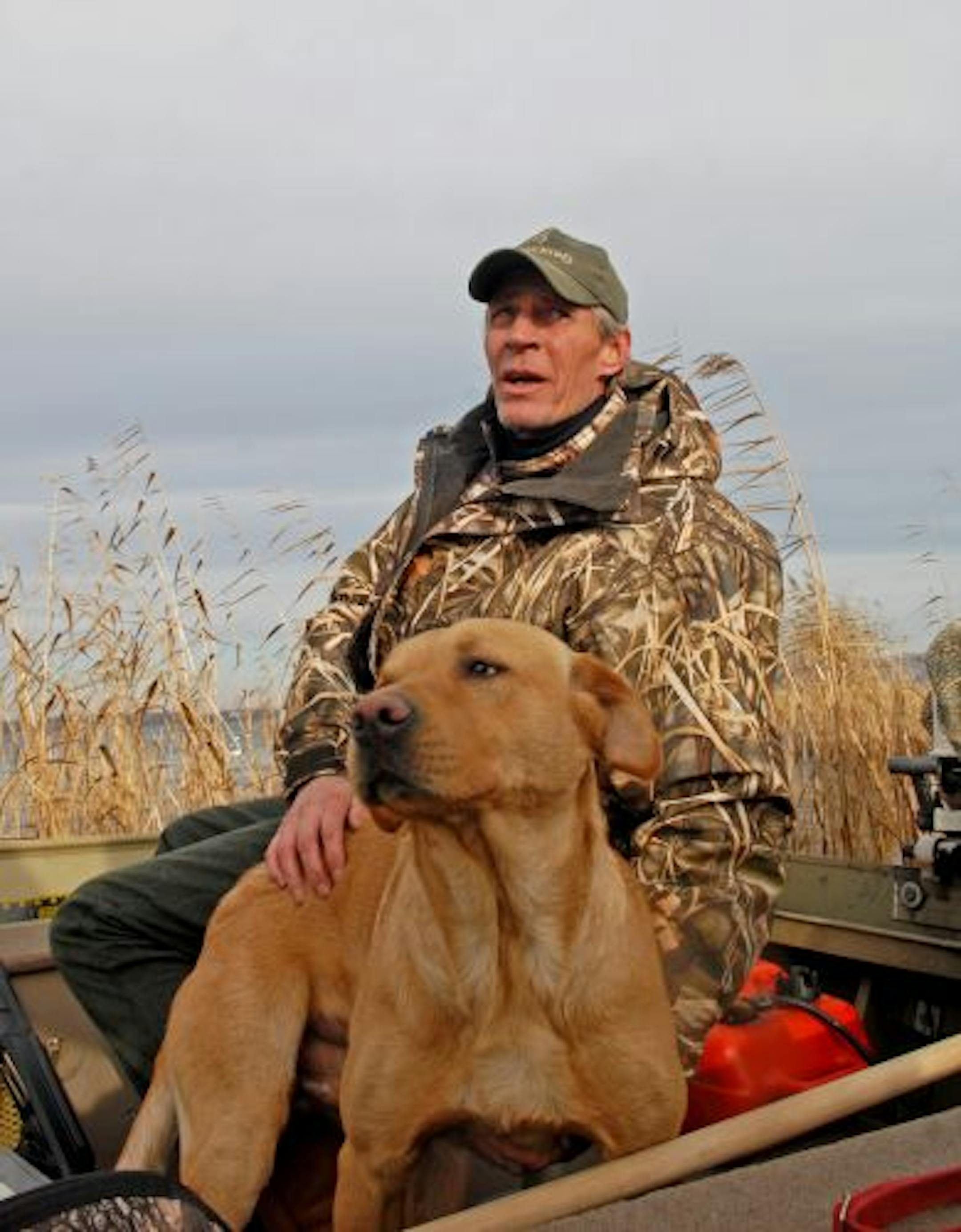 Tom Hexum of Rochester has hunted the Mississippi River near Weaver, Minn., for decades. Here he pets Pete, a yellow Labrador, on the last day of the 2009 Minnesota duck season, while scanning the sky over the river for birds.