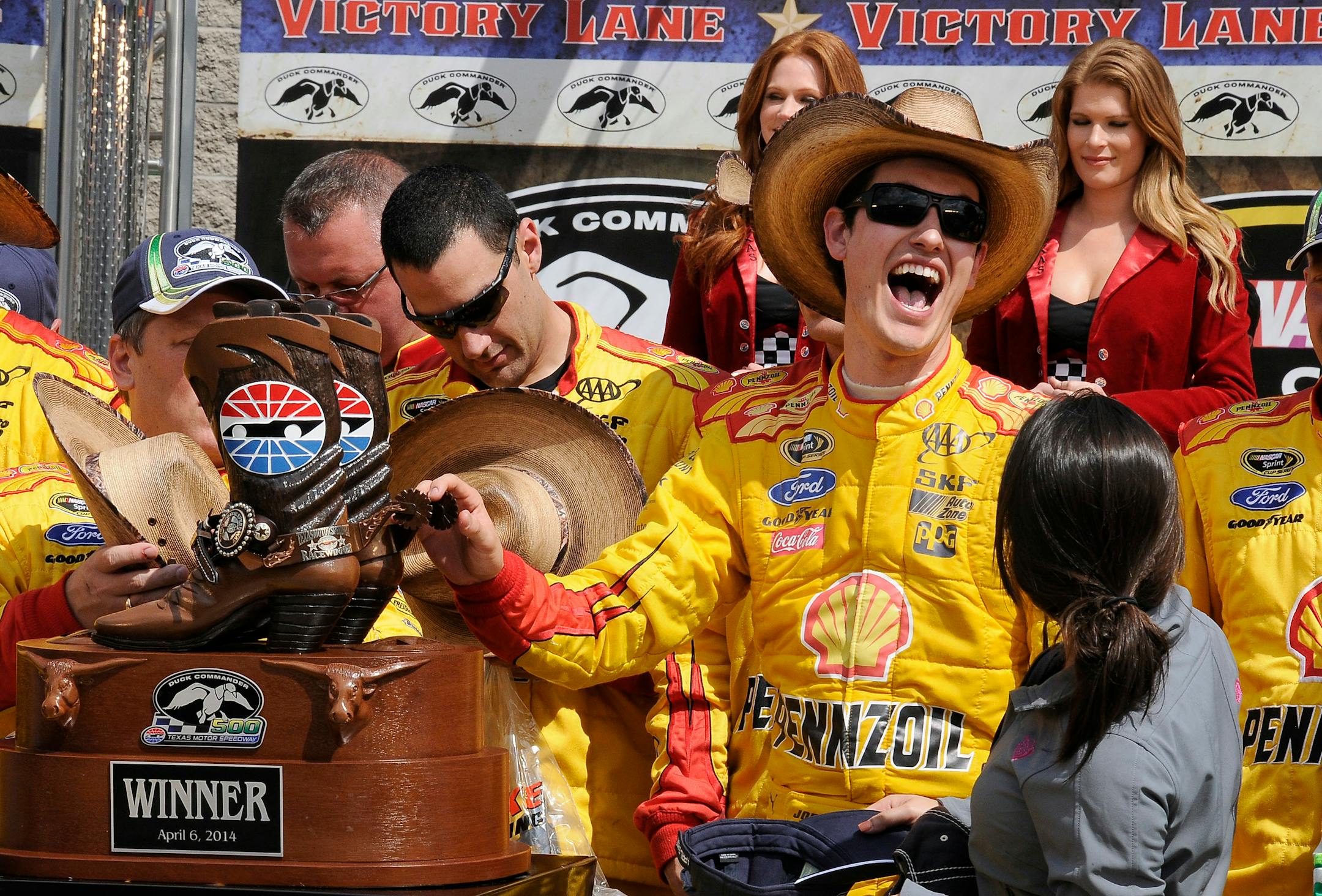 Joey Logano touches the winner trophy in victory lane after winning the NASCAR Sprint Cup Series auto race at Texas Motor Speedway Monday, April 7, 2014, in Fort Worth, Texas. (AP Photo/Larry Papke)