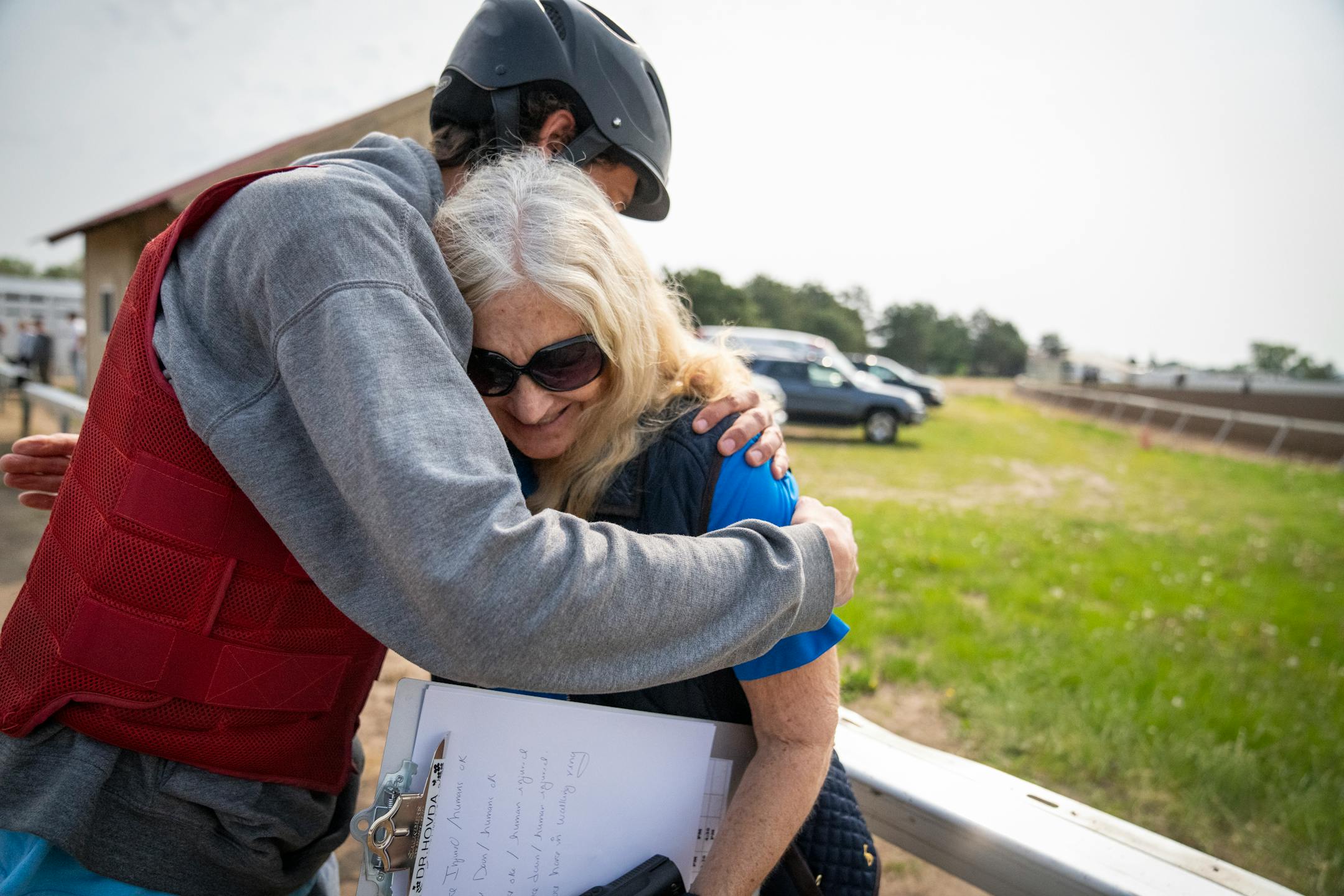 Dr. Lynn Hovda gets a hug from Vinny Panetta, an assistant starter at the starting gates of Canterbury Park in Shakopee, Minn.
