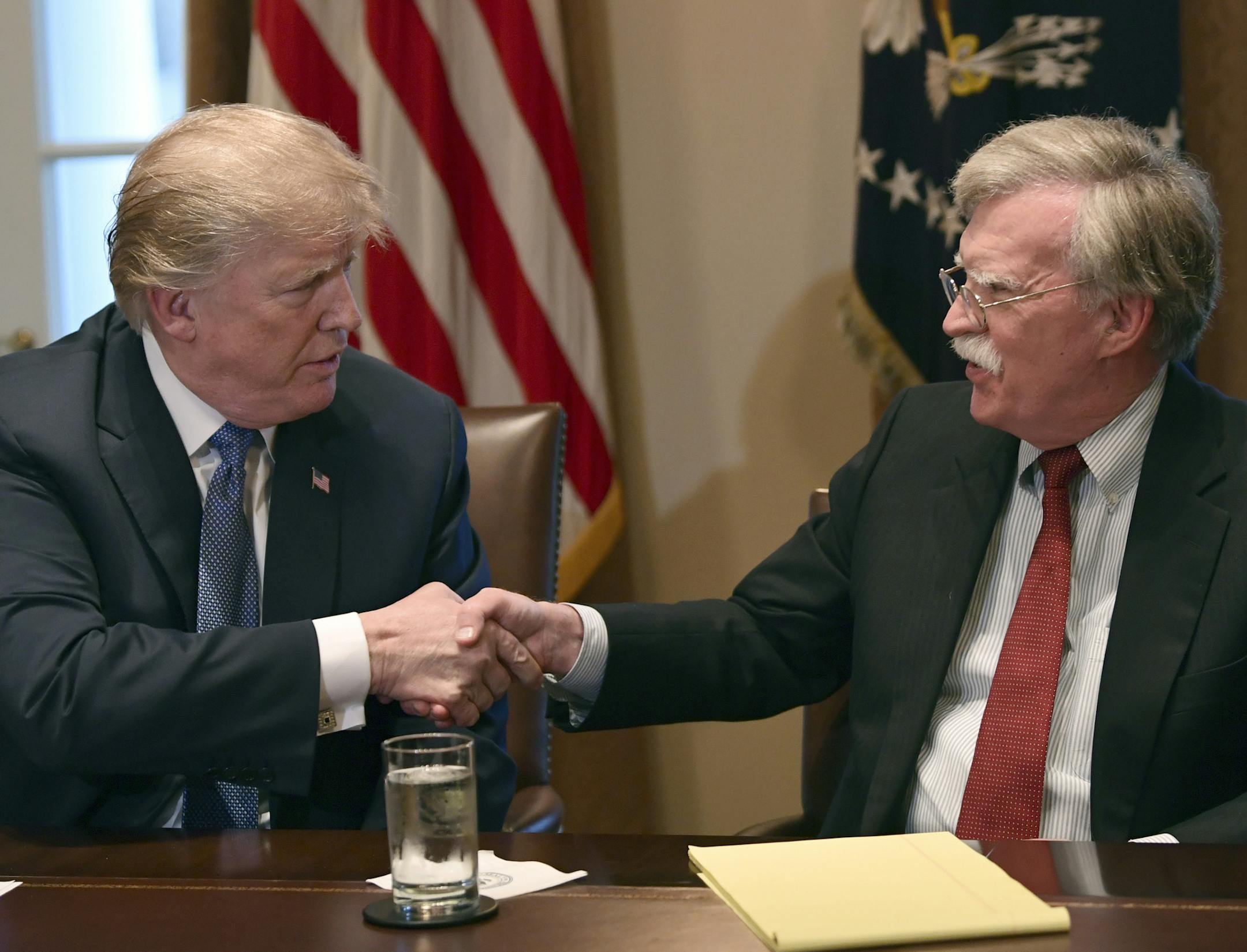 President Donald Trump, left, shakes hands with national security adviser John Bolton in the Cabinet Room of the White House in Washington, Monday, April 9, 2018, at the start of a meeting with military leaders. (AP Photo/Susan Walsh)