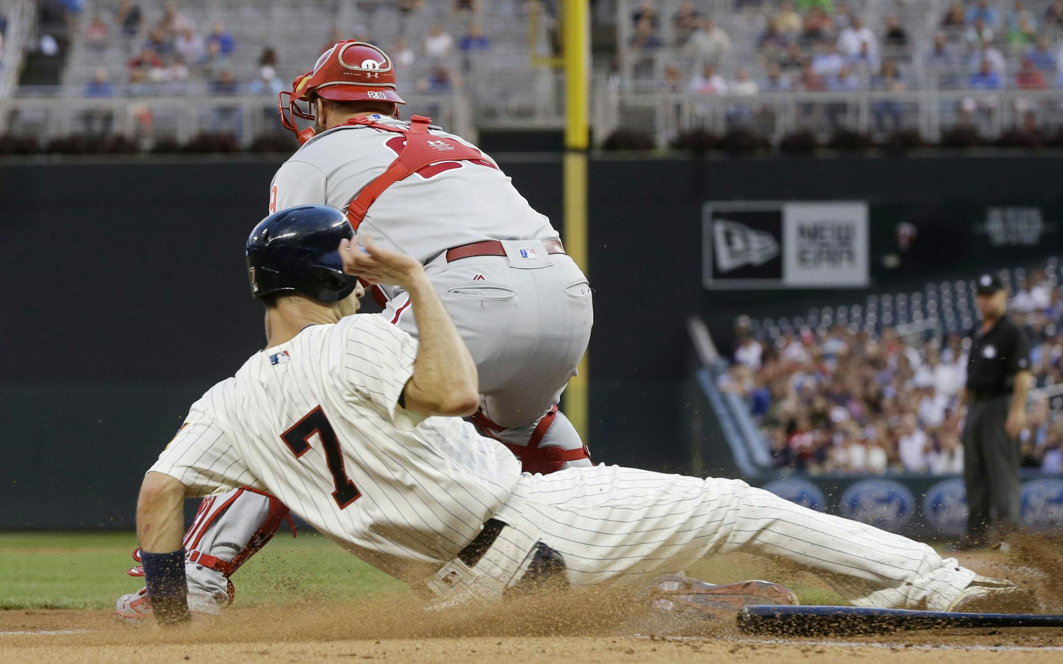 Minnesota Twins' Joe Mauer slides in to score on a Trevor Plouffe double as Philadelphia Phillies' Cameron Rupp waits for the throw in the first inning of a baseball game Wednesday, June 22, 2016, in Minneapolis. (AP Photo/Jim Mone)