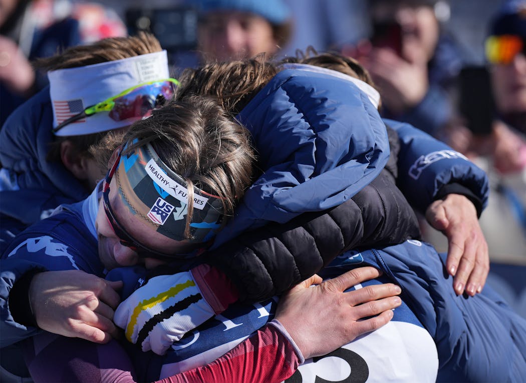 Gus Schumacher is enveloped by his teammates after his stunning win on Sunday. He is only the third American man to win a World Cup cross-country race. 