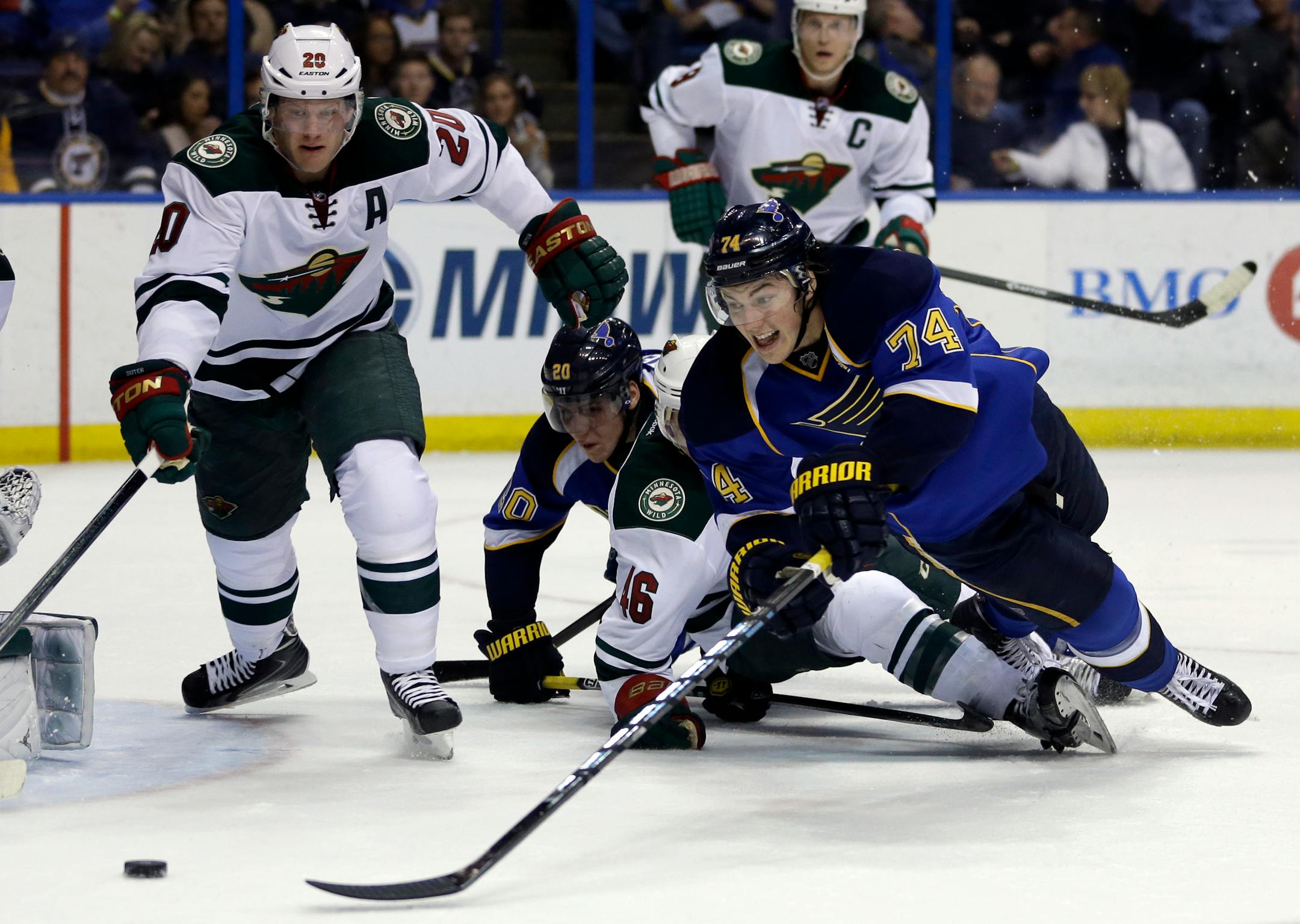 St. Louis Blues' T.J. Oshie (74) and Minnesota Wild's Ryan Suter (20) reach for a loose puck during the second period of an NHL hockey game Thursday, March 27, 2014, in St. Louis. (AP Photo/Jeff Roberson