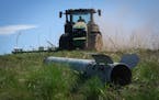 A fragment of a Russian missile is seen in the foreground as a farmer works on his field in Izium, Kharkiv region, Ukraine, Saturday, Apr. 20, 2024. (