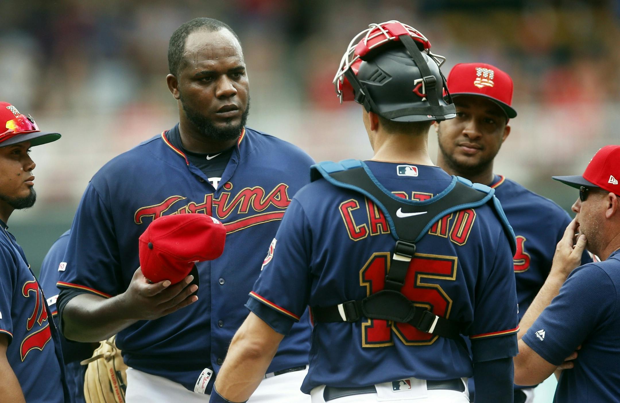 Minnesota Twins pitcher Michael Pineda, left, holds his cap as he gets a mound visit from catcher Jason Castro and pitching coach Wes Johnson, right, after giving up a walk to load the bases against the Texas Rangers in the third inning of a baseball game Saturday, July 6, 2019, in Minneapolis. (AP Photo/Jim Mone)