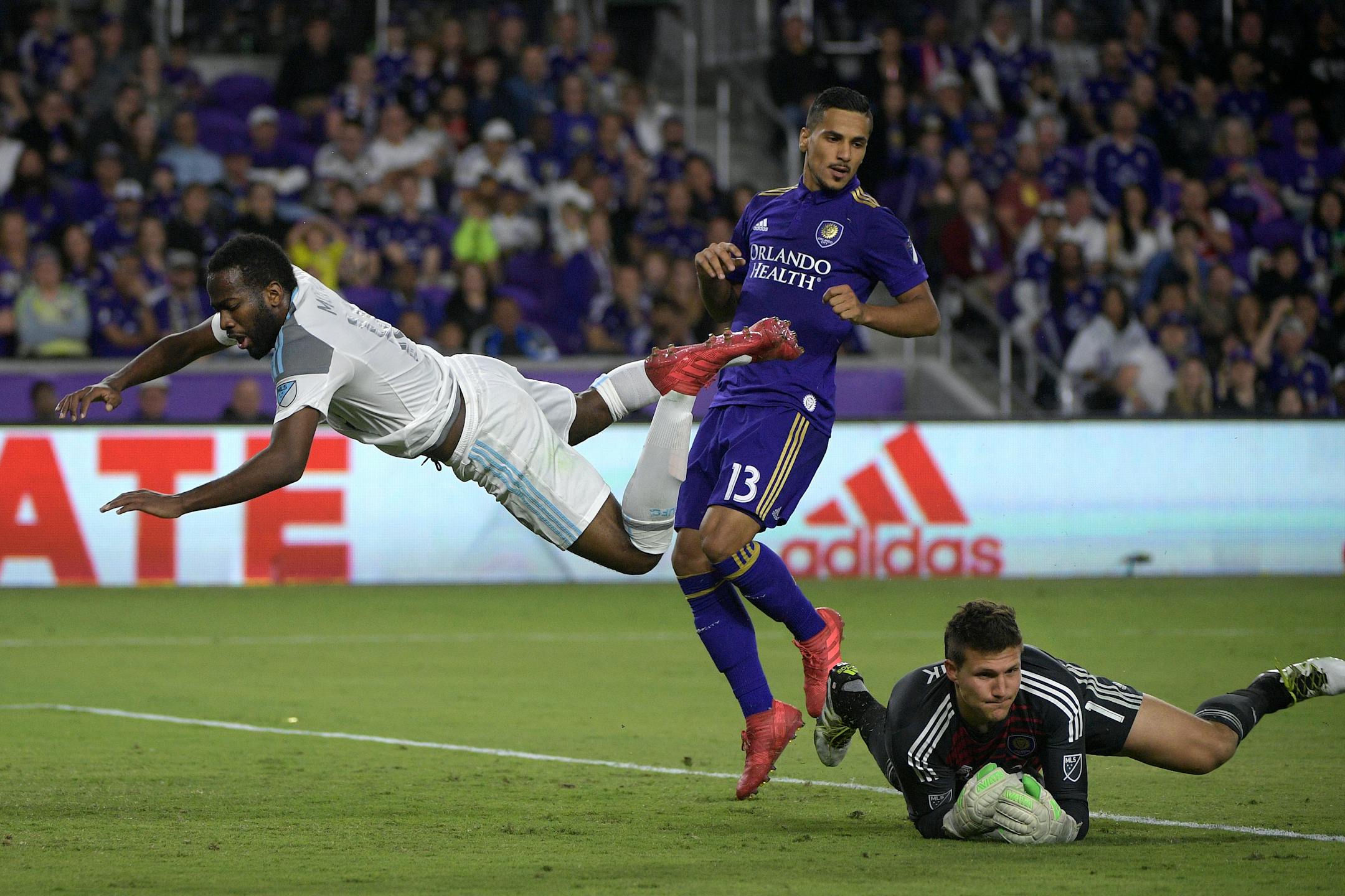 Minnesota United midfielder Kevin Molino (18) flies through the air as Orlando City goalkeeper Joseph Bendik (1) makes a save during the first half of an MLS soccer game Saturday, March 10, 2018, in Orlando, Fla. (Phelan M. Ebenhack for the Star-Tribune) ORG XMIT: OTKMINN103