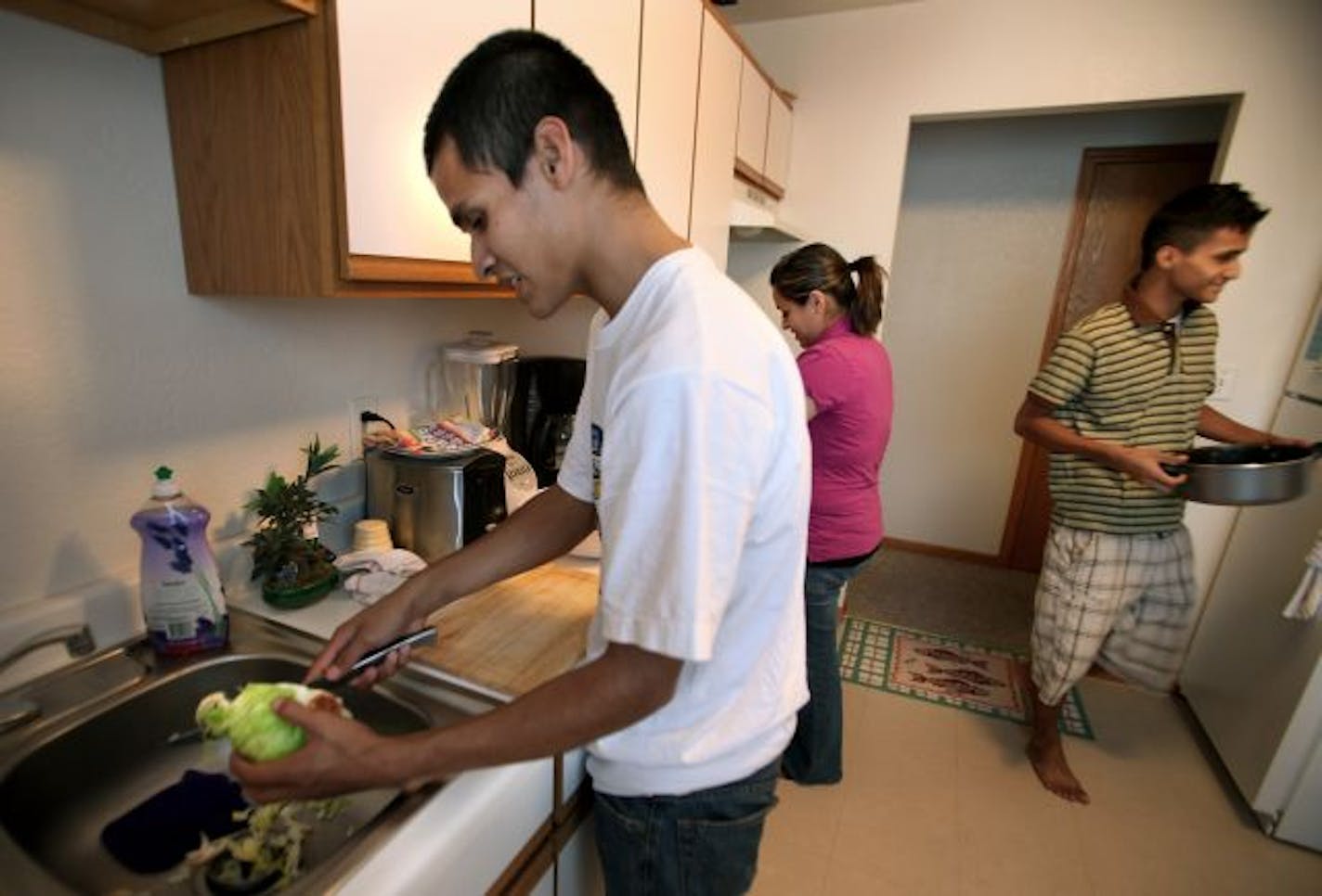 Pablo Mira, left, his twin, Rene, and their sister, Silvia, cooked dinner for their mother at their South St. Paul home. Pablo had a Brown College recruiter scheduled for a visit, but he was being detained at the time by immigration authorities.