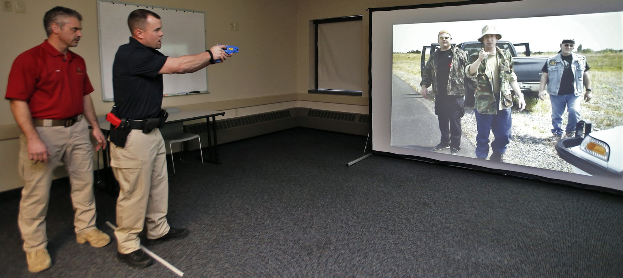 Rasmussen College in Eagan has opened a new police training facility with a number of scenario training rooms that depict situations police may find themselves in public encounters. Mike Ardolf, Law Enforcement Skills Coordinator, and Dave Eichman, law enforcement student, enact some of these situations. Ardolf, left, instructed Eichman in a traffic stop situation depicted on a video screen where it was necessary to taser a group of men who approaching in a threatening manner. (MARLIN LEVISON/ST