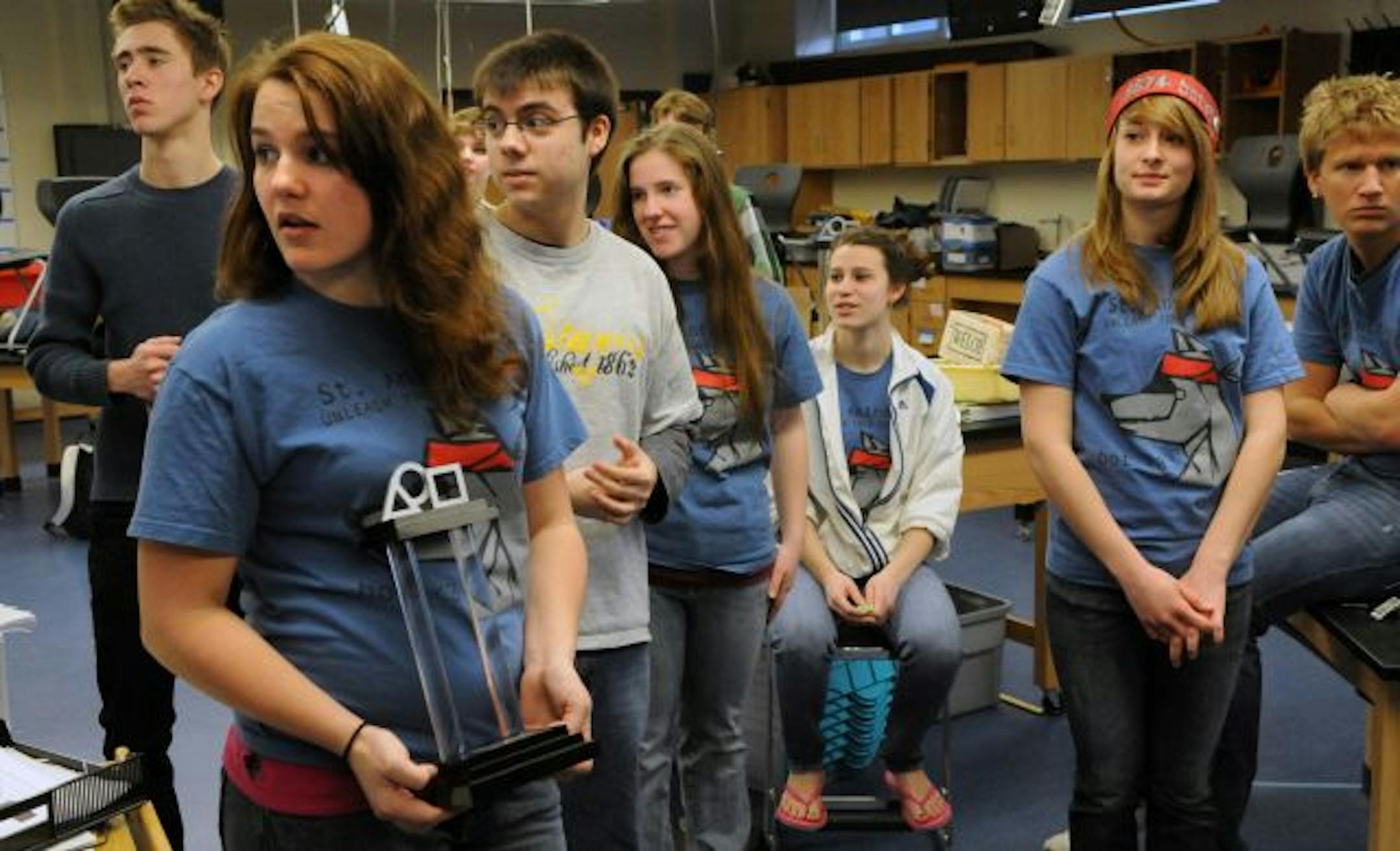 From left, St. Anthony Village High School robotics team members Robin Leiberwirth, Jyll Tusa, Natalie Hanley (background), Dan Marino, Sorcha Nix, Lydia Stucki, Emily Hugill and Thomas Busch. Tusa is holding a trophy the team won in a regional competition. Their robot already has been shipped to Atlanta.