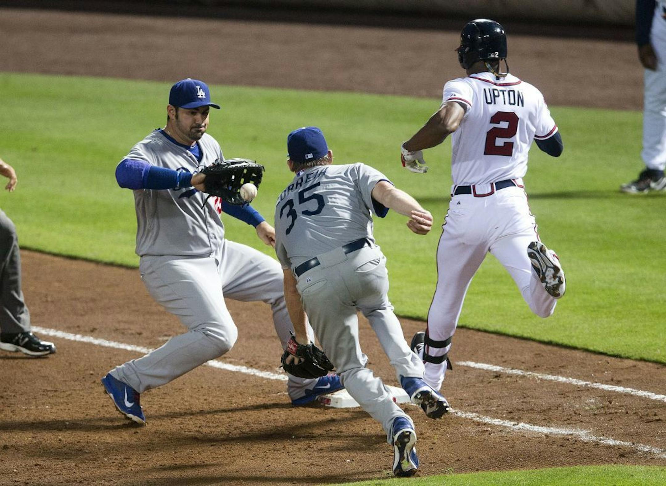 Los Angeles Dodgers pitcher Kevin Correia (35) flips the ball to first baseman Adrian Gonzalez (23) to force out Atlanta Braves' B.J. Upton (2) in the sixth inning of a baseball game Monday, Aug. 11, 2014 in Atlanta.