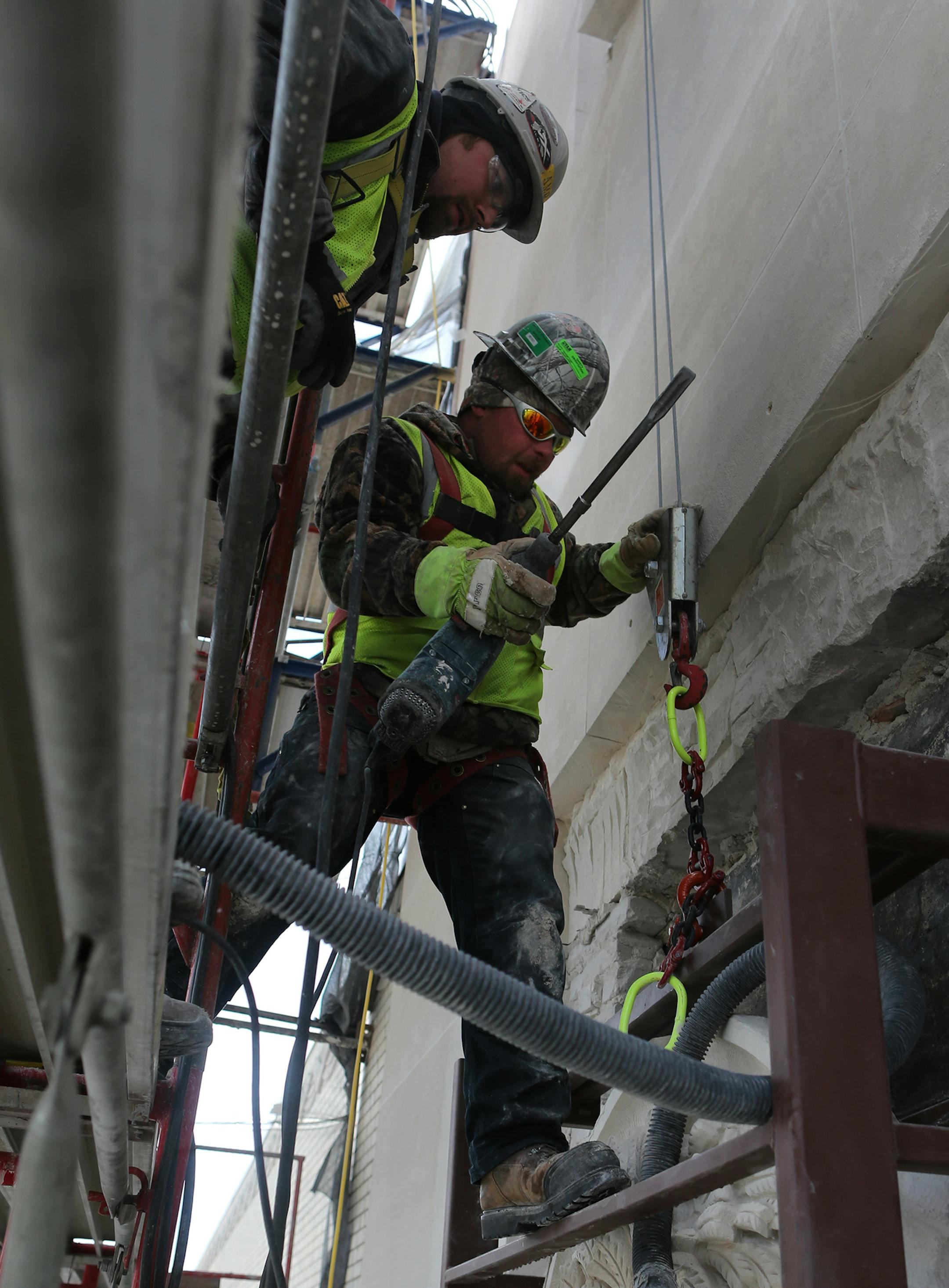 Travis Hudlow (left), Bobby Tufts and Kyle Purinton (bottom) worked to remove the second of six historic medallions from the Star Tribune building. ] MCKENNA EWEN mckenna.ewen@startribune.com - April 1, 2014, Minneapolis Star Tribune