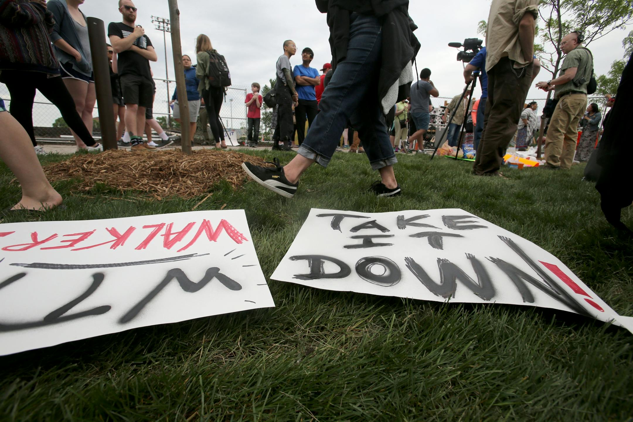 A controversial new sculpture at the Walker Art Center that prompted an outcry among Minnesota's American Indian communities will be dismantled, the director said Saturday. Here, protestors walk past signs on the ground outside the Walker Sculpture Garden Saturday, May 27, 2017, in Minneapolis, MN.