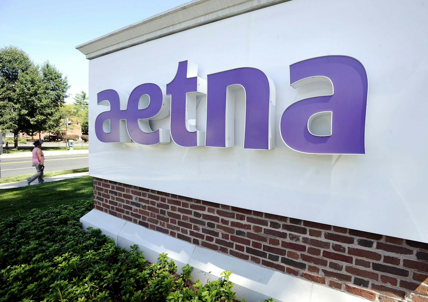 In this Tuesday, Aug. 19, 2014, photo, a pedestrian walks past a sign for Aetna Inc., at the company headquarters in Hartford, Conn. Aetna will become the latest health insurer to chop its participation in the Affordable Care Act&#xed;s public exchanges when it trims its presence to four states for 2017, from 15 this year. The nation&#xed;s third-largest insurer said late Monday, Aug. 15, 2016, that a second-quarter pre-tax loss of $200 million from its individual insurance coverage helped it de