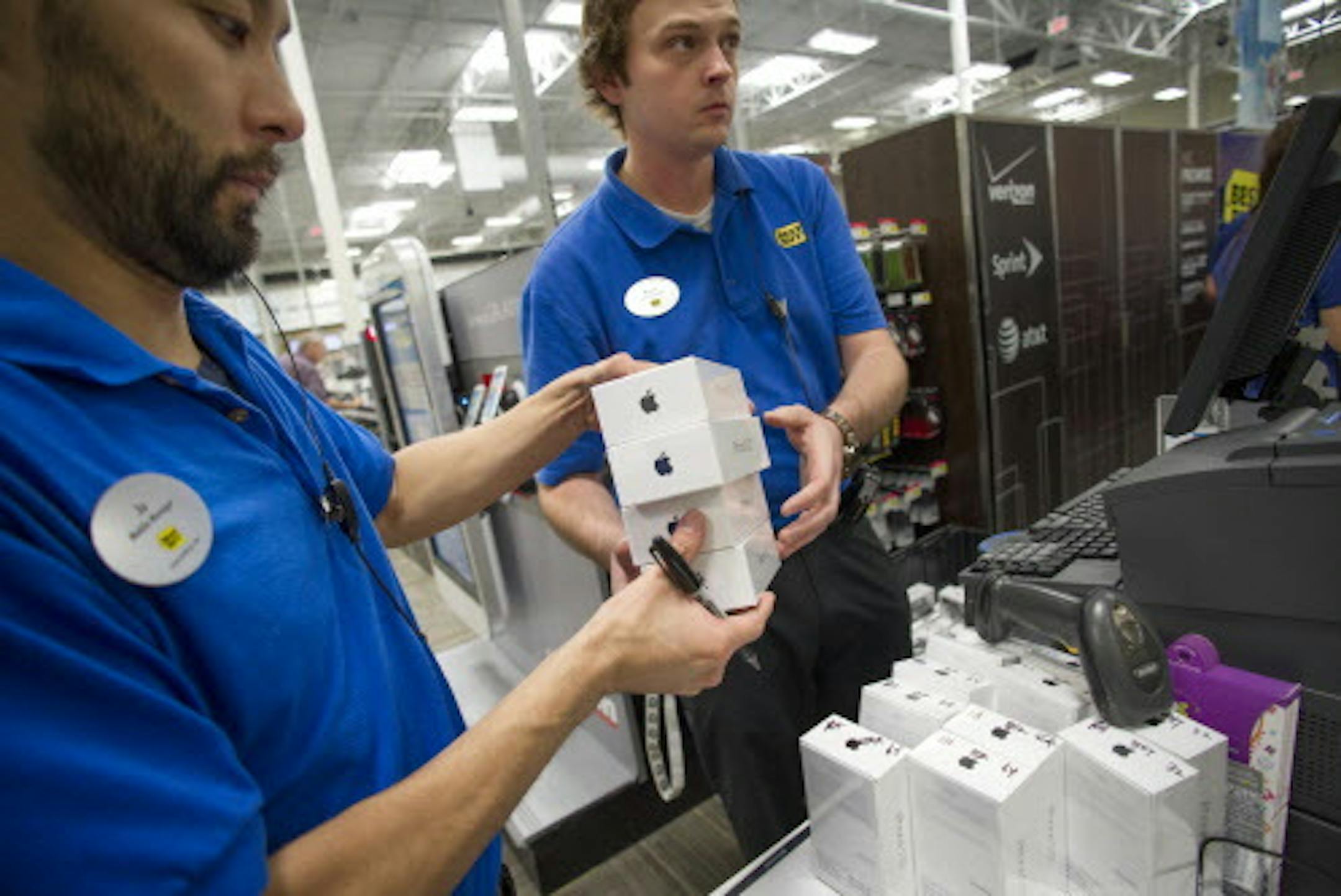 FILE - In this Sept. 20, 2013 file photo, Managers Ju Lee, left, and Brad Deep get iPhone 5s and iPhone 5c phones ready for sale on the day of their release, at a Best Buy in Atlanta. Appleís quarterly earnings are still sagging even as the sales of its iPhones are rising, a vexing phenomenon feeding investor worries about whether stiffer competition in the mobile device market will continue to undercut the companyís prosperity. (AP Photo/John Amis, File)