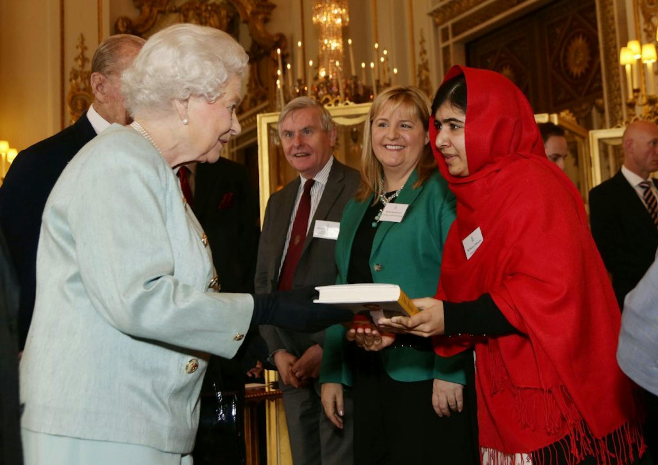 Malala Yousafzai gives a copy of her book to Britain's Queen Elizabeth II during a reception for youth, education and the Commonwealth at Buckingham Palace, London, Friday Oct. 18, 2013.