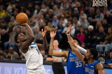 Minnesota Timberwolves guard Anthony Edwards (1) shot over the defense of Dallas Mavericks forward Christian Wood (35) and Mavericks guard Spencer Din