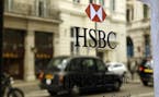 A taxi is reflected as it drives past an HSBC plaque in St James's Street in London, Tuesday, June 9, 2015. HSBC Holdings, Britain's largest bank by m