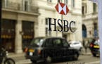 A taxi is reflected as it drives past an HSBC plaque in St James's Street in London, Tuesday, June 9, 2015. HSBC Holdings, Britain's largest bank by m