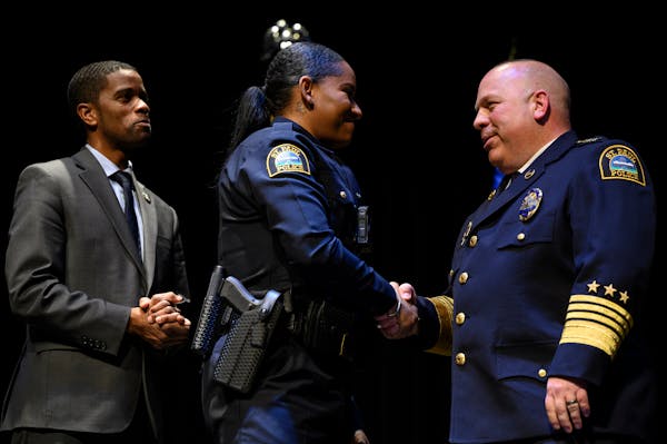 From left, St. Paul Mayor Melvin Carter watched as St. Paul Police Academy graduate Kristina Ijomah received her badge and a handshake from former Pol