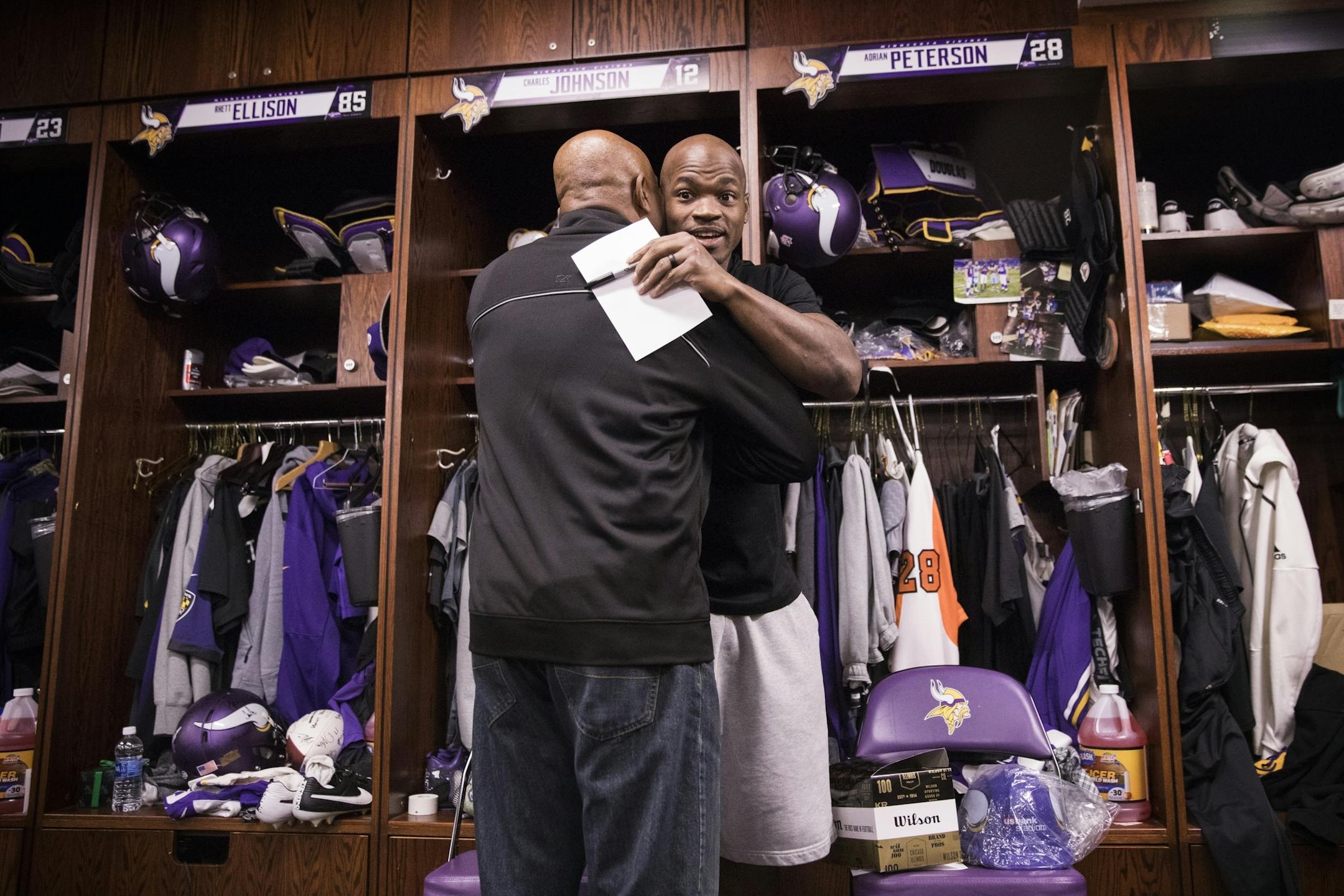 Adrian Peterson gets a hug from former Viking Greg Coleman at his locker.