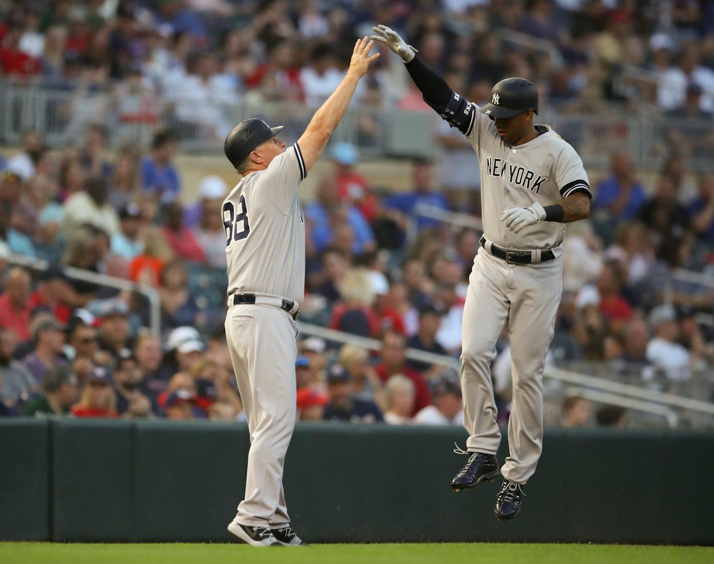 Yankees center fielder Aaron Hicks high-fived third base coach Phil Nevin after a third-inning solo home run off Jake Odorizzi.