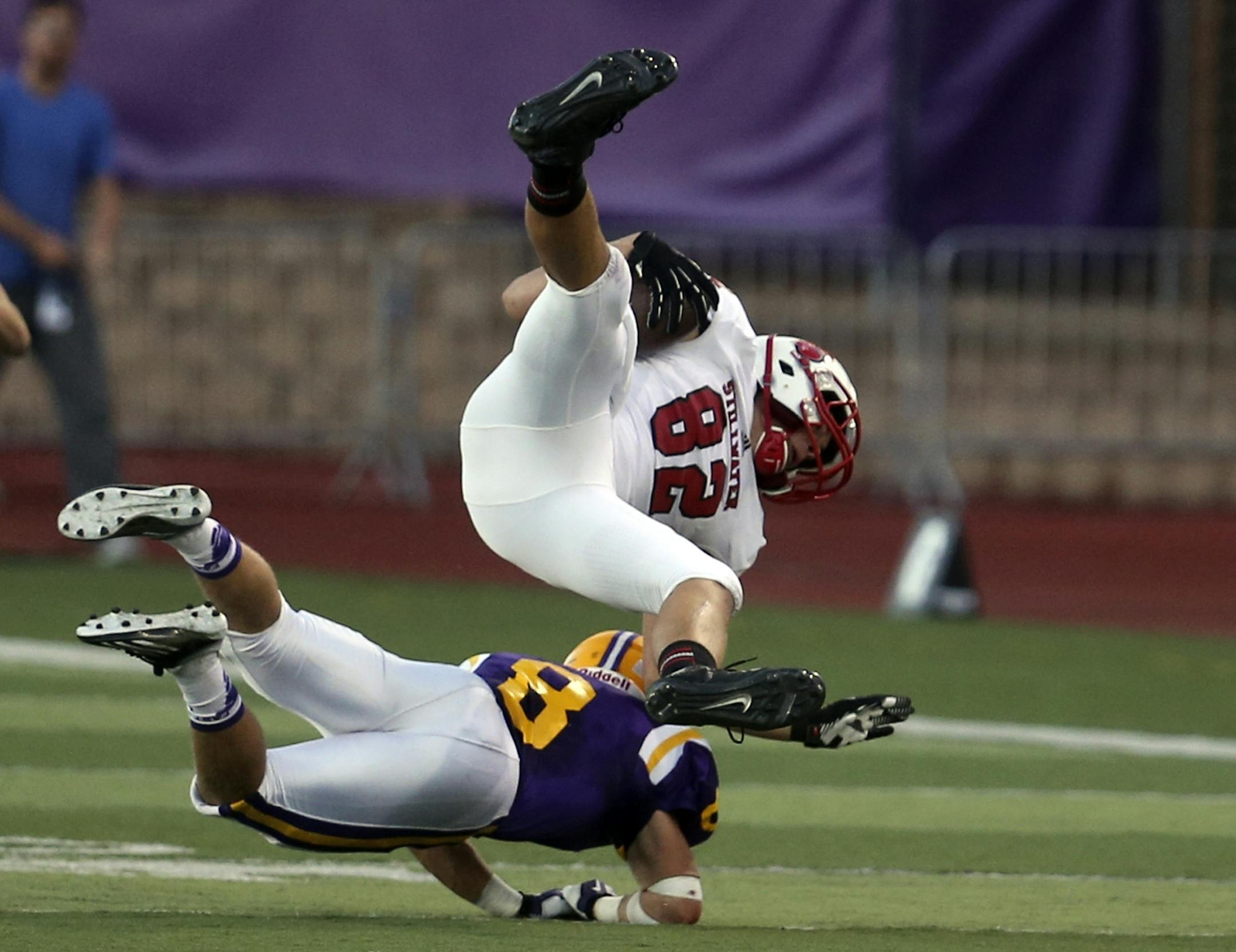 After a long first half pass reception Stillwater receiver Matt Anderson (82) is upended by CDH defender Blake Banham (8) Friday, Sept. 13, 2013, at the University of St. Thomas , in St. Paul, MN.