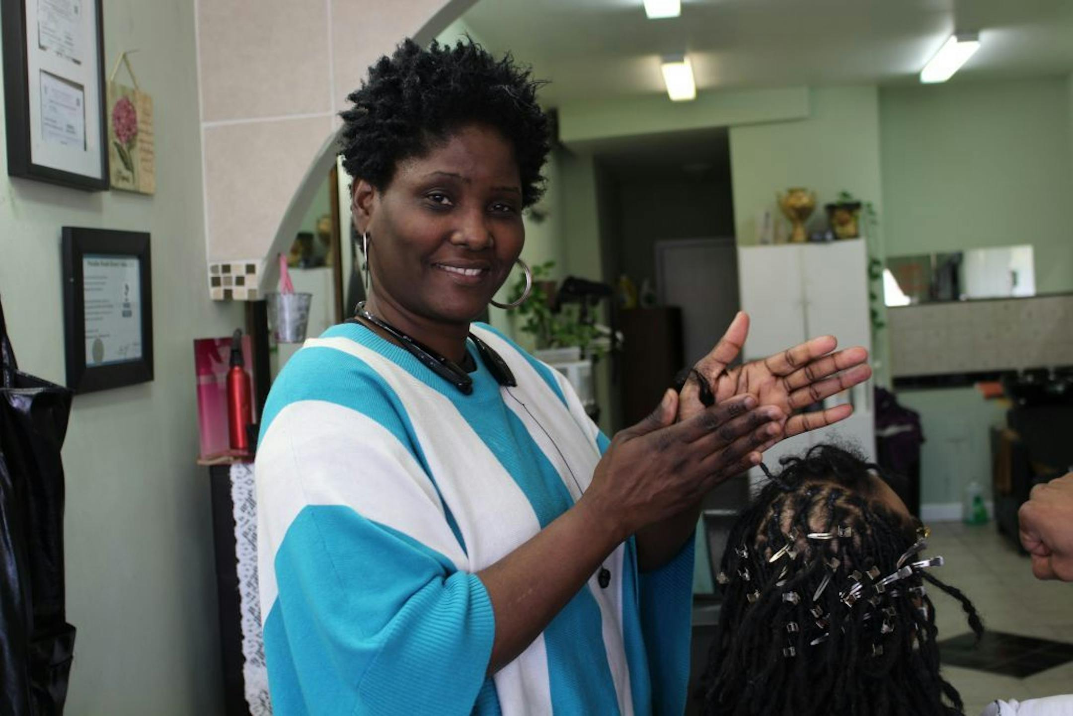 Marie Egbujor, owner of Paradise Beauty Salon, braids hair in her business adjacent to the fire site. She says business has not fully rebounded and remains slow.