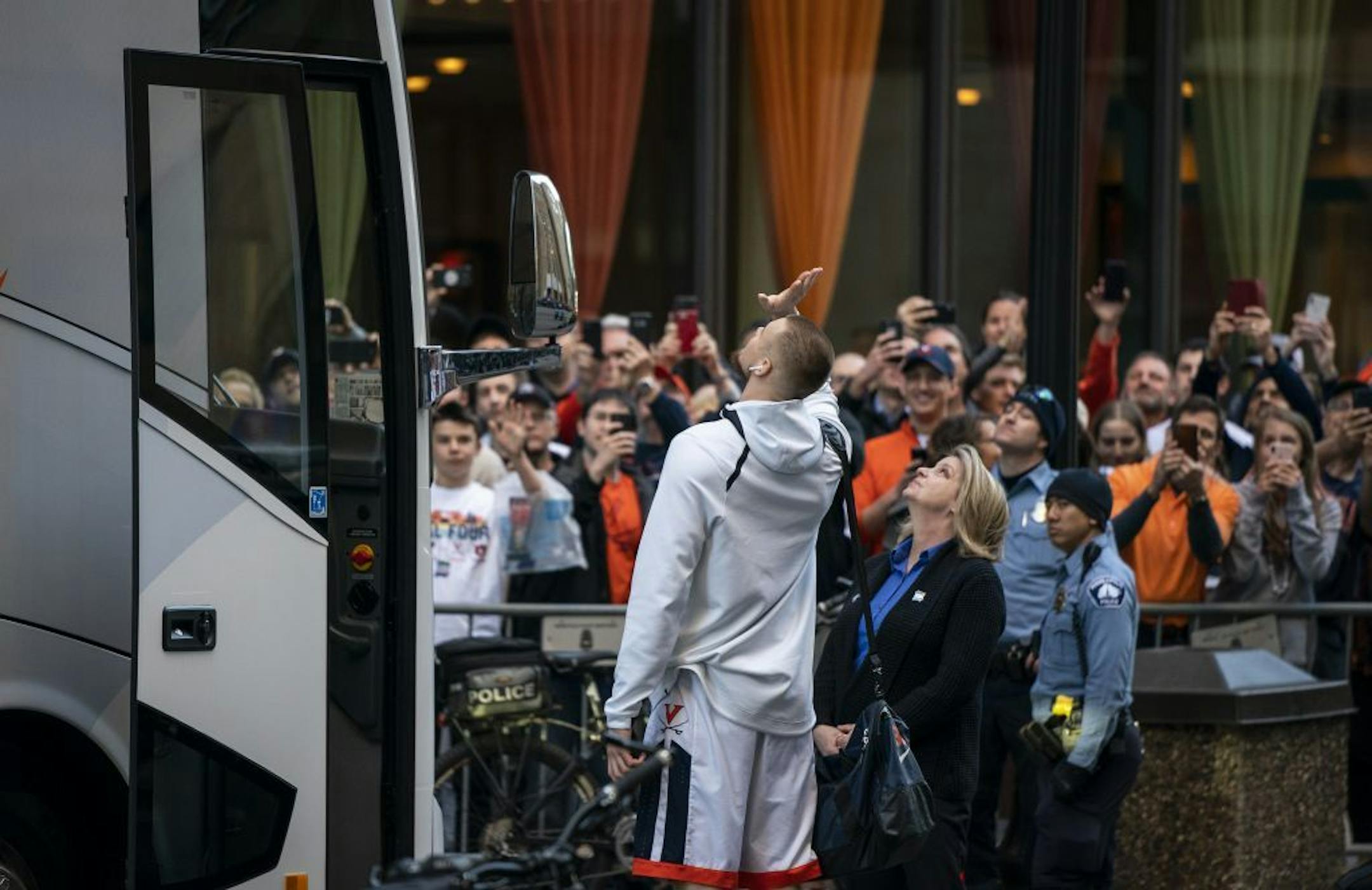 University of Virginia basketball player Jack Salt waves to someone above as he boards the bus.