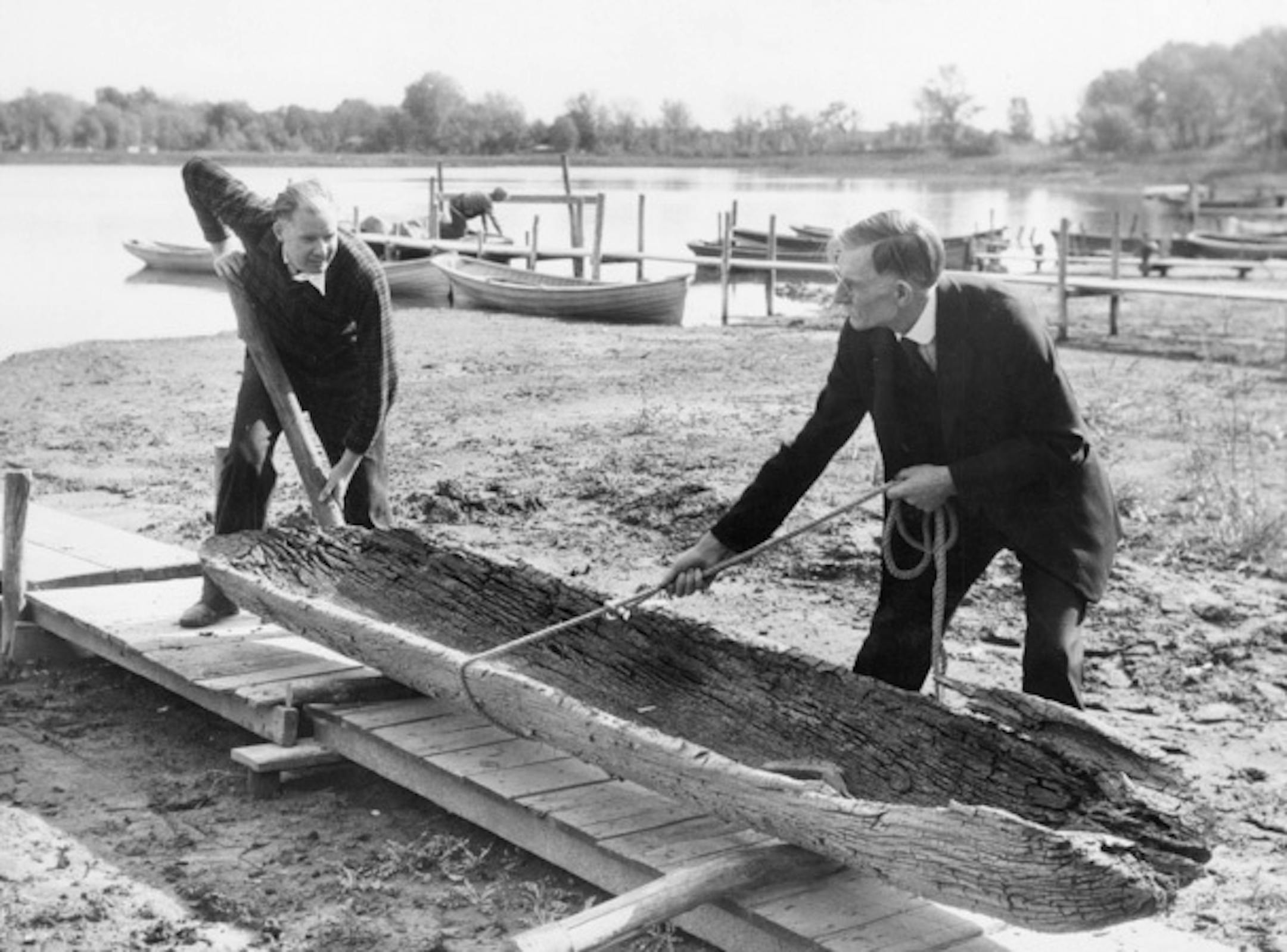 Helmer and Gustave Gunnarson, who discovered the Lake Minnetonka North Arm Dugout Canoe, removed if from the water in front of their cabin in August 1934. The artifact was located near the end of the Gunnarson family dock about 90 feet from the shoreline because of receding water caused by a severe drought. In normal conditions, the canoe would have been under several feet of water.