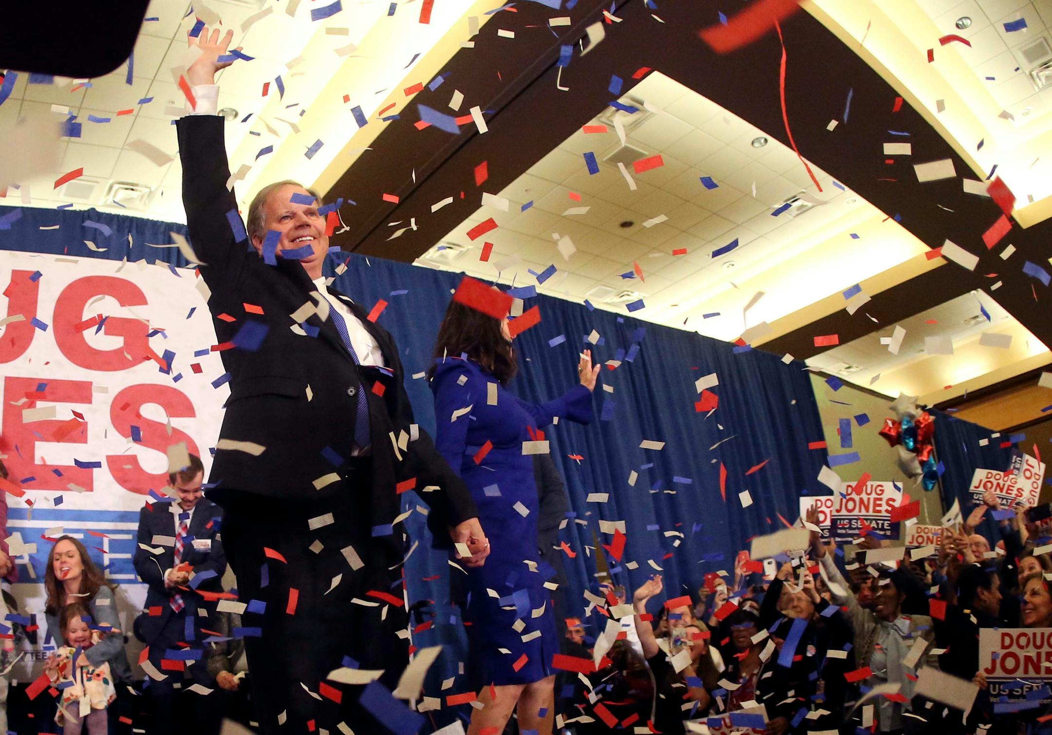 Confetti falls as Democrat Doug Jones and his wife Louise wave to supporters Tuesday, Dec. 12, 2017, in Birmingham, Ala. In a stunning victory aided by scandal, Democrat Doug Jones won Alabama's special Senate election on Tuesday, beating back history, an embattled Republican opponent and President Donald Trump, who urgently endorsed GOP rebel Roy Moore despite a litany of sexual misconduct allegations. (AP Photo/John Bazemore)