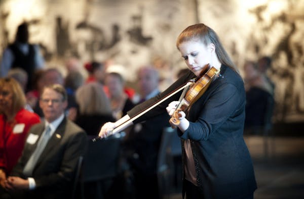 Minnesota Orchestra board chairman Richard Davis, left, listened as orchestra concertmaster Erin Keefe played during the group's annual meeting Tuesda