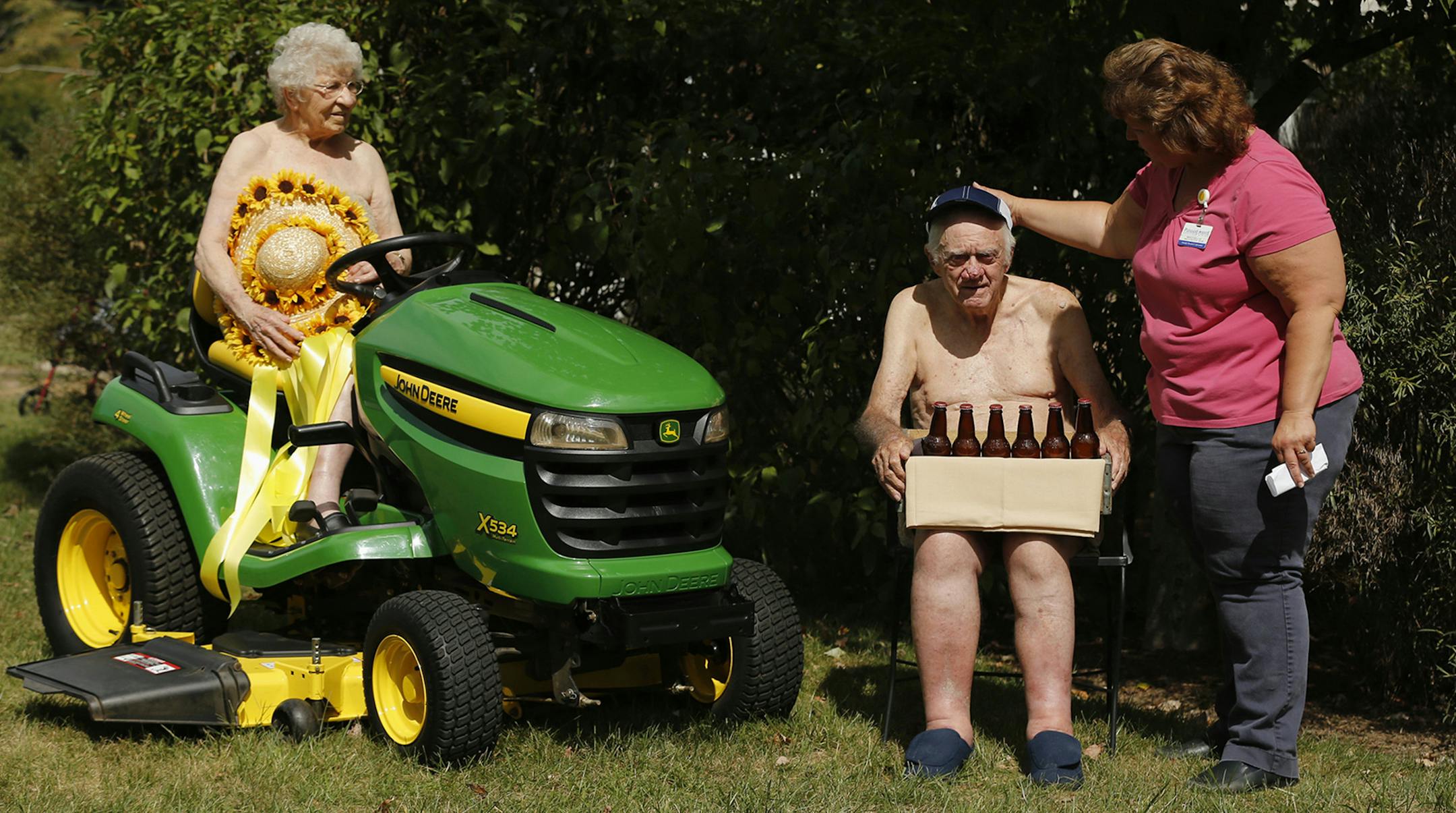 Michelle Clapper, right, activity director of Pleasant Pointe Assisted Living, adjusts the hat of resident Richard Taylor, 89, as Clapper sets up a pose that includes resident Jo Pyle, 91, for Pleasant Pointe's 2016 calendar in which residents appear nude Thursday, Sept. 10, 2015 in Barberton, Ohio. The women are in fact covered with secured towels and the men are wearing shorts. Proceeds from the calendar go to Magic City Kiwanis for the Esther Ryan Shoe Fund, which provides shoes for children