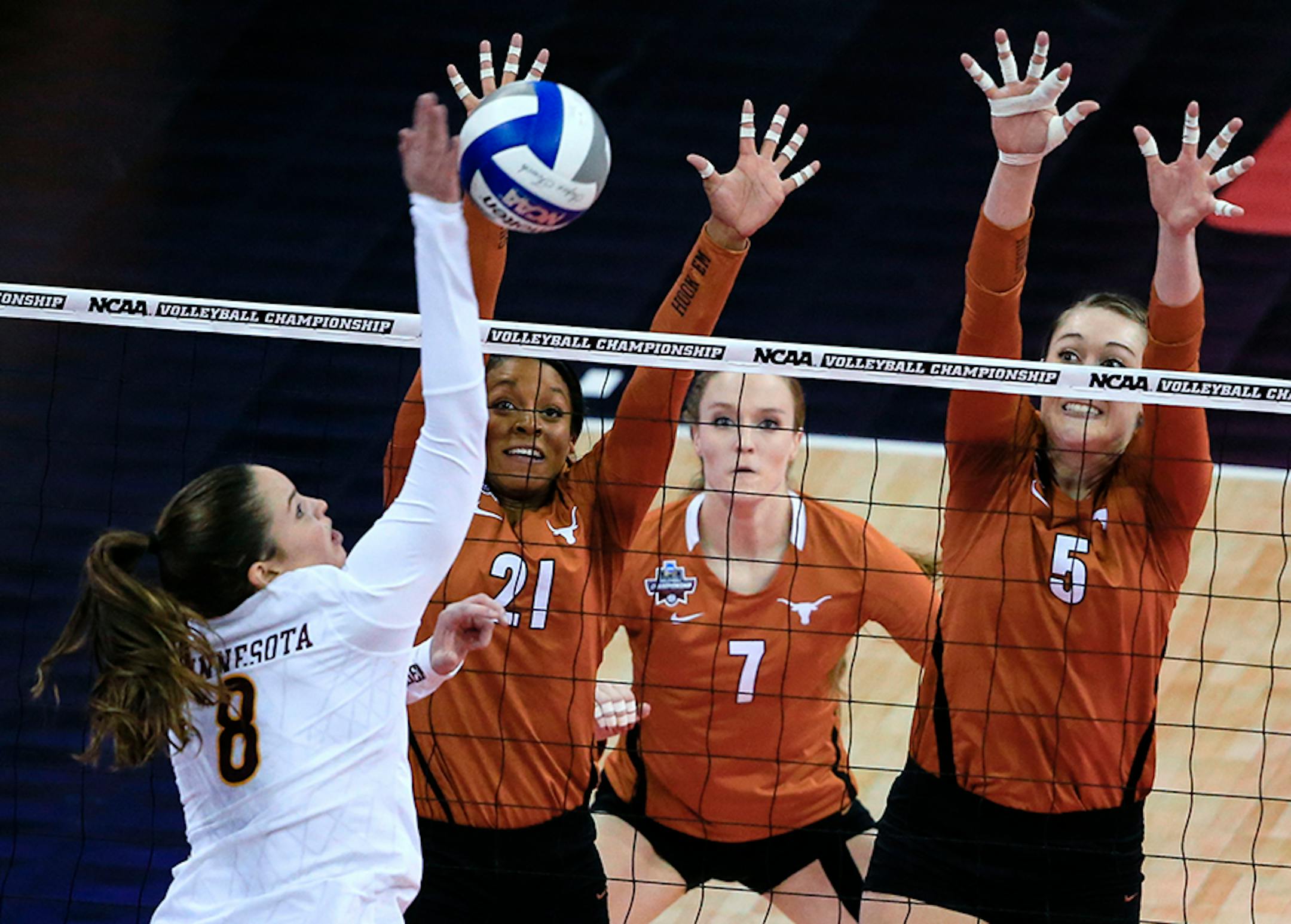 Minnesota's Sarah Wilhite (8) spikes the ball against Texas' Chloe Collins (21), Nicole Dalton (7) and Molly McCage (5) during an NCAA women's volleyball tournament semifinal in Omaha, Neb., Thursday, Dec. 17, 2015.