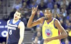 Golden State Warriors' Kevin Durant, right, celebrates a score as Minnesota Timberwolves' Nemanja Bjelica watches during the first half of an NBA bask