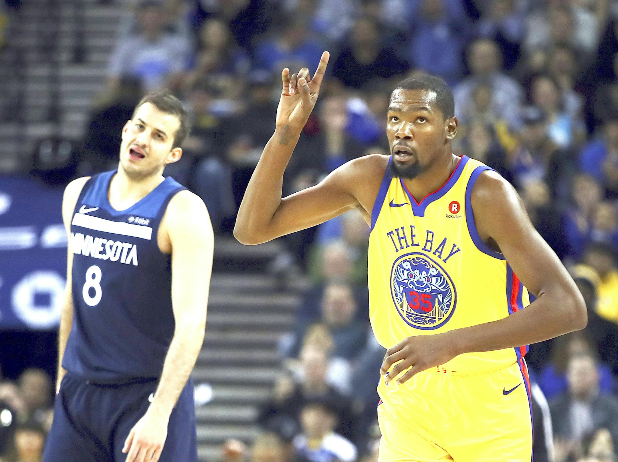 Golden State Warriors' Kevin Durant, right, celebrates a score as Minnesota Timberwolves' Nemanja Bjelica watches during the first half of an NBA basketball game Thursday, Jan. 25, 2018, in Oakland, Calif. (AP Photo/Ben Margot) ORG XMIT: MIN2018012523510270