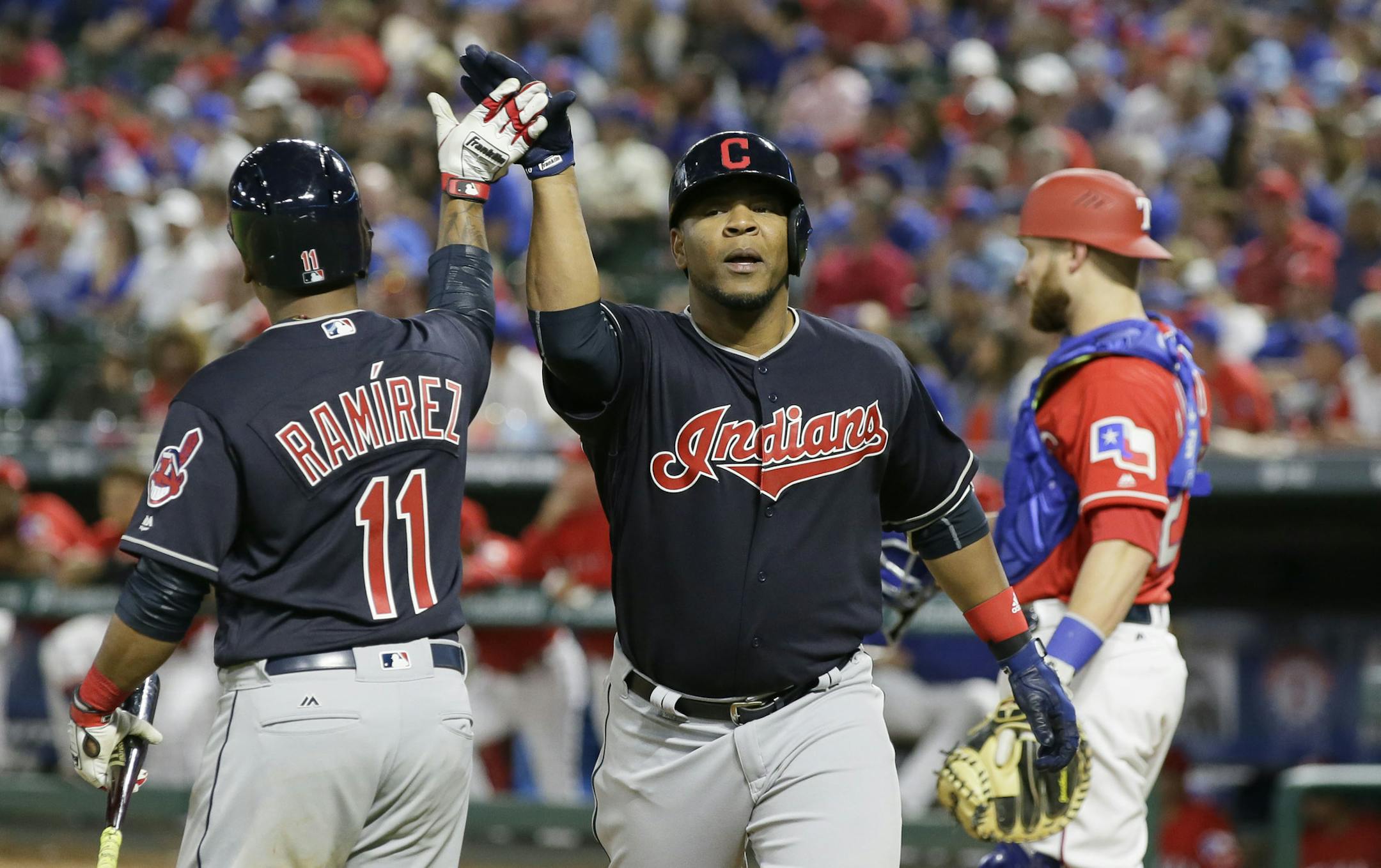 Cleveland Indians Edwin Encarnacion, center, is congratulated after a solo home run during the eighth inning of an opening day baseball game against the Texas Rangers in Arlington, Texas, Monday, April 3, 2017. (AP Photo/LM Otero)