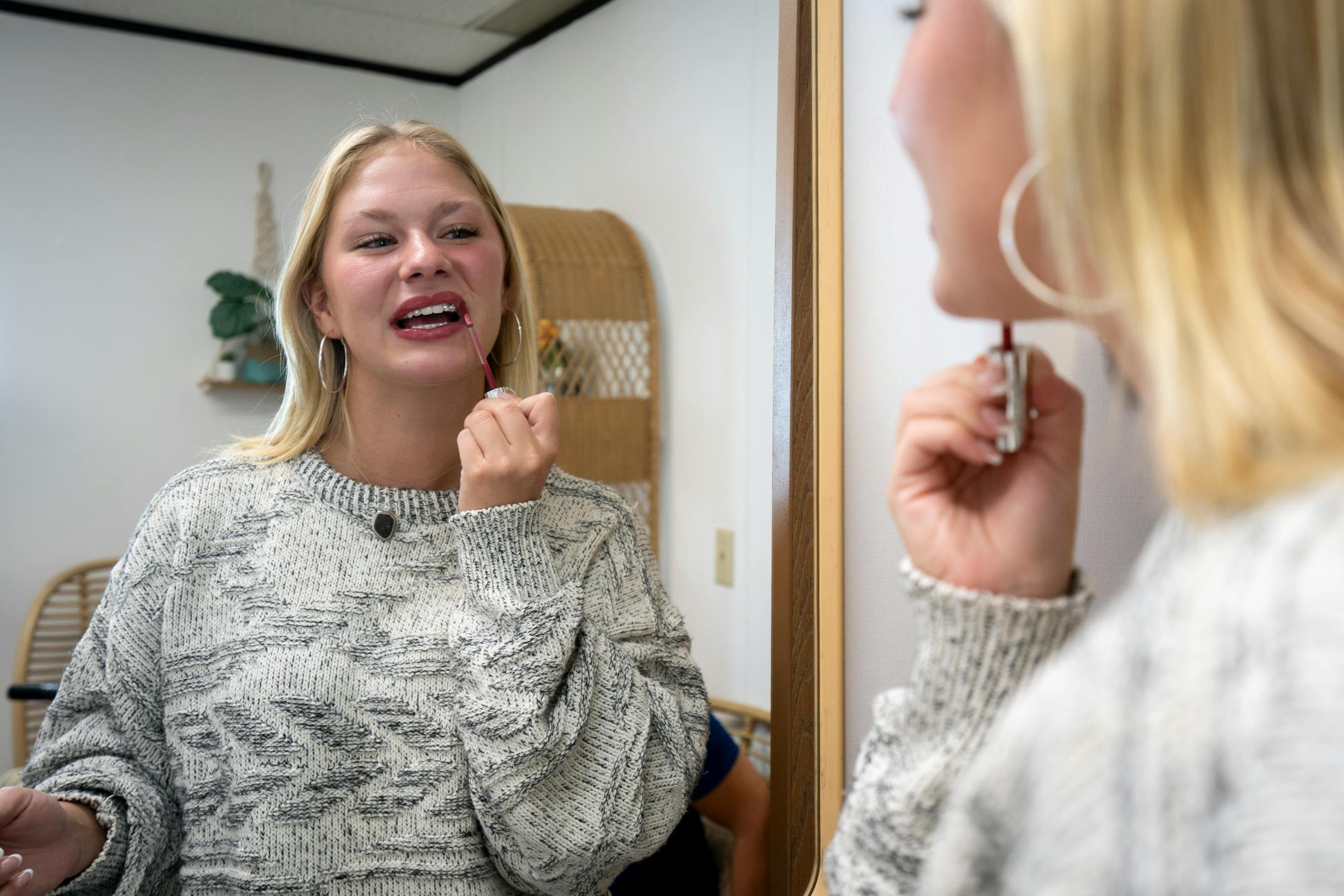 Josie Wicka applies lip gloss while she checks out her newly gemmed teeth at Pearly Whites MN in Burnsville, Minn. on Thursday, June 29, 2023.
