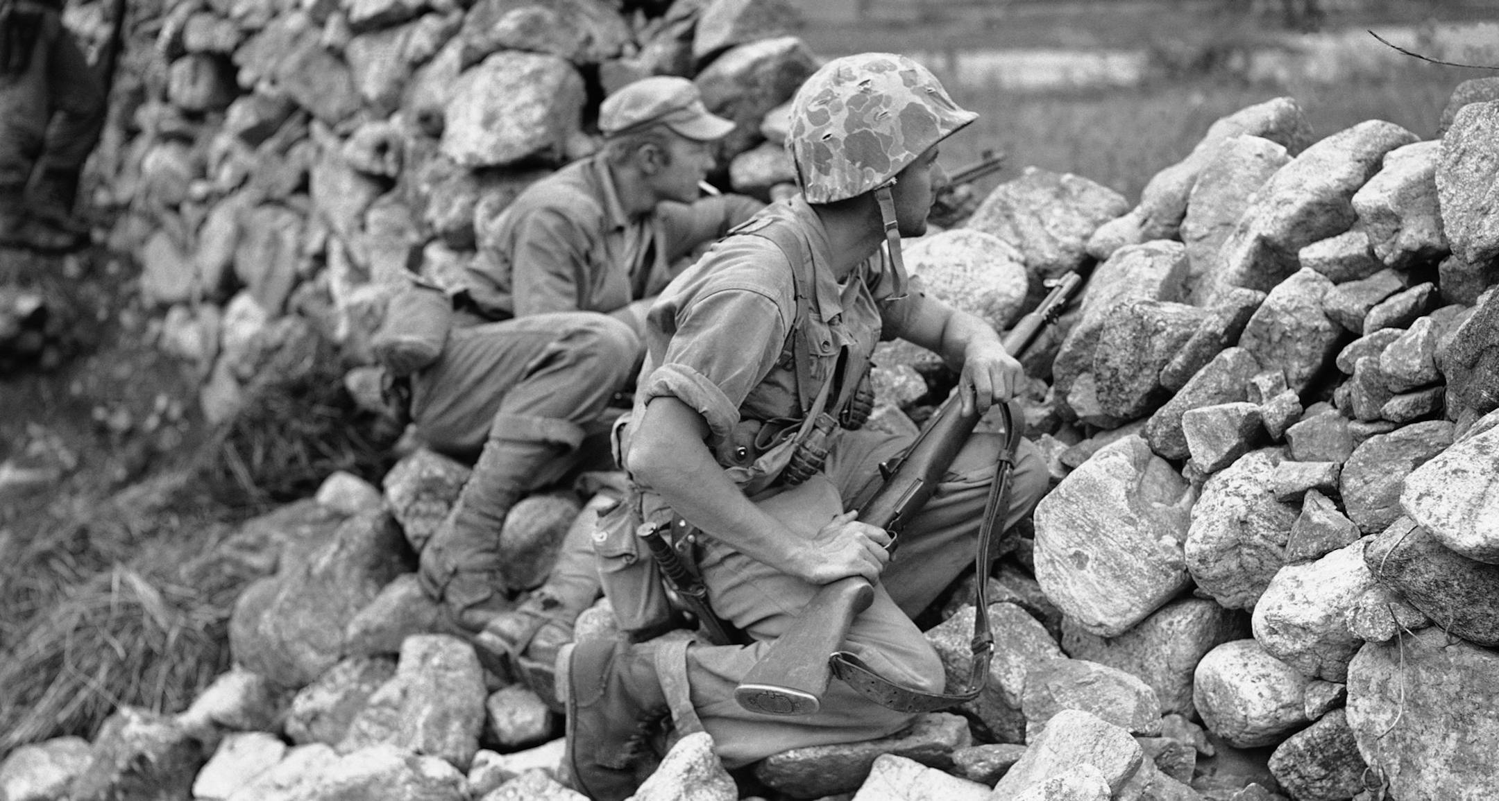 Two U.S. soldiers are on the alert as they take protection behind stone wall on Korean front near Choyang River in North Korea on June 3, 1951. Cpl. Richard G. Clark, foreground, of Westwood, New Jersey, wears helmet as Pfc. Joseph M. Nadorozny, of 973 east 13th St., Brooklyn, New York, puffs on cigarette. (AP Photo/E.N.Johnson) ORG XMIT: APHS291795