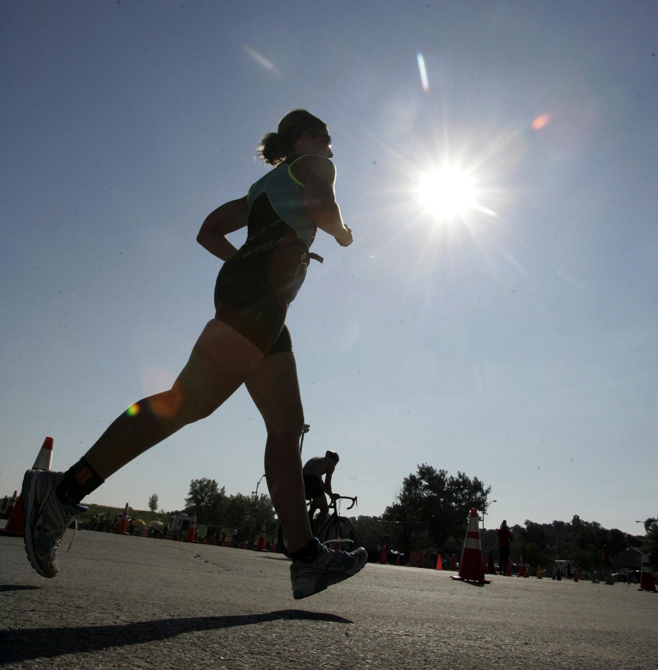 The sun shines above an athlete as she starts the running leg of the Michigan City Triathlon in Washington Park Saturday, Aug. 10, 2013 in Michigan City, Ind. (AP Photo/The LaPorte Herald-Argus, Bob Wellinski)