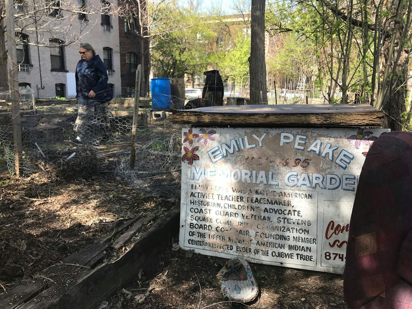 Cheryl Magnell, steward of the Emily Peake Memorial Garden, walks past a faded sign for the garden on Tuesday, May 7, 2019. The owner of the property plans to turn the garden space into a parking lot.